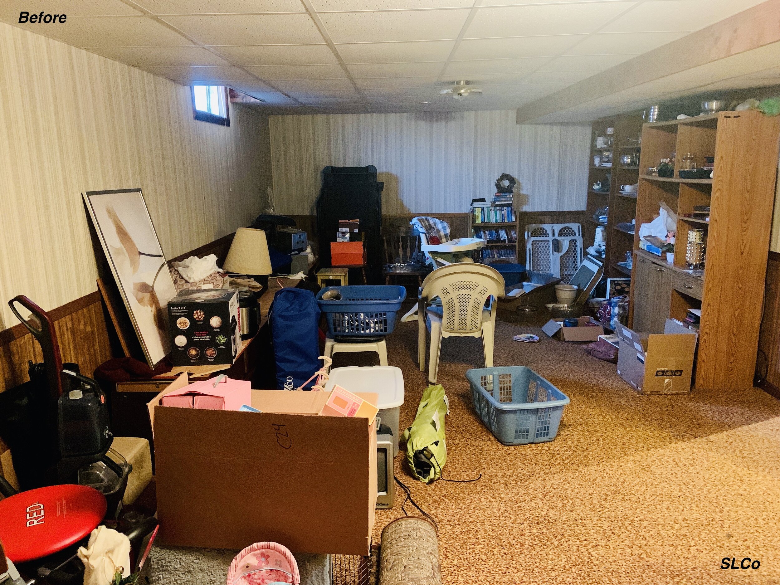 Before photo of basement with items and toys on floor and in stacks.