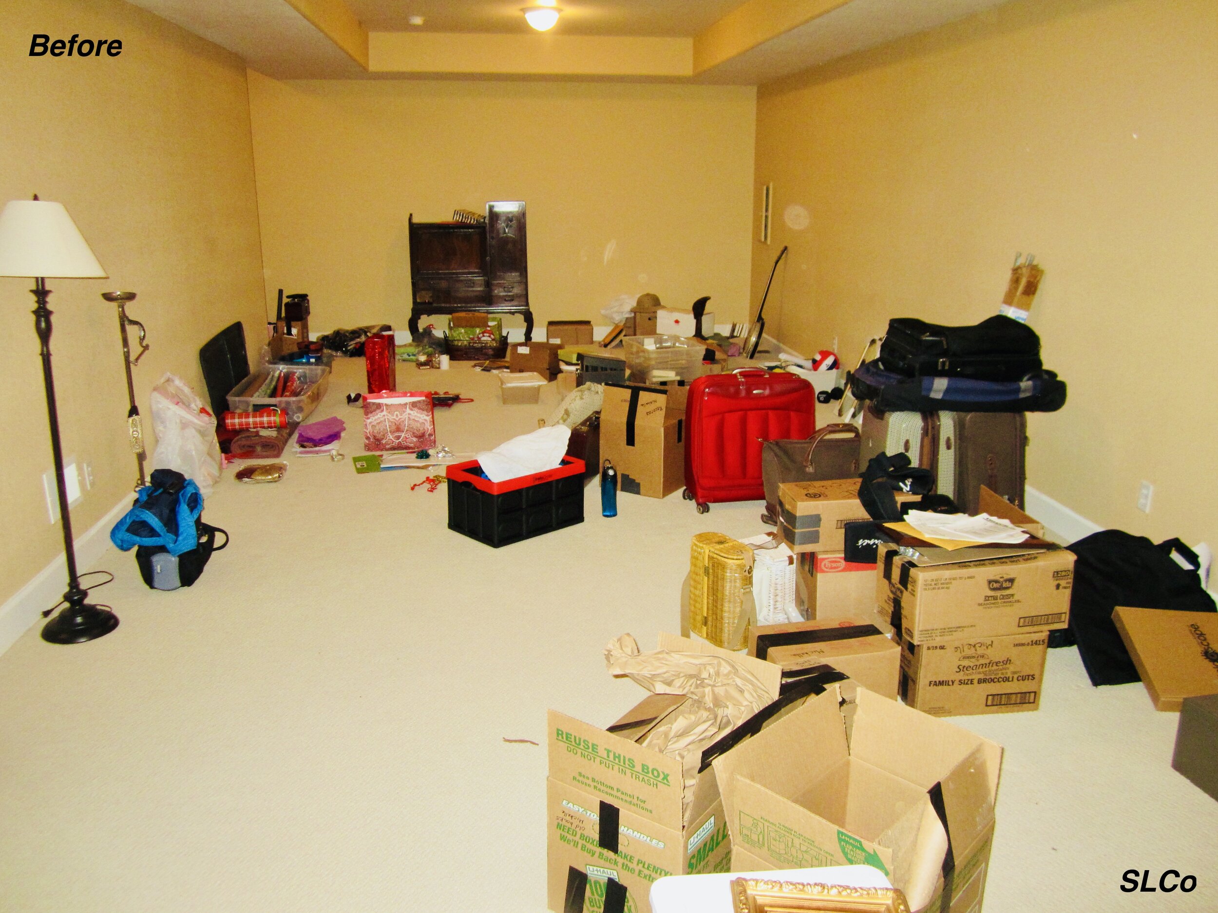 Before photo of large basement with boxes and containers open and covering floor.