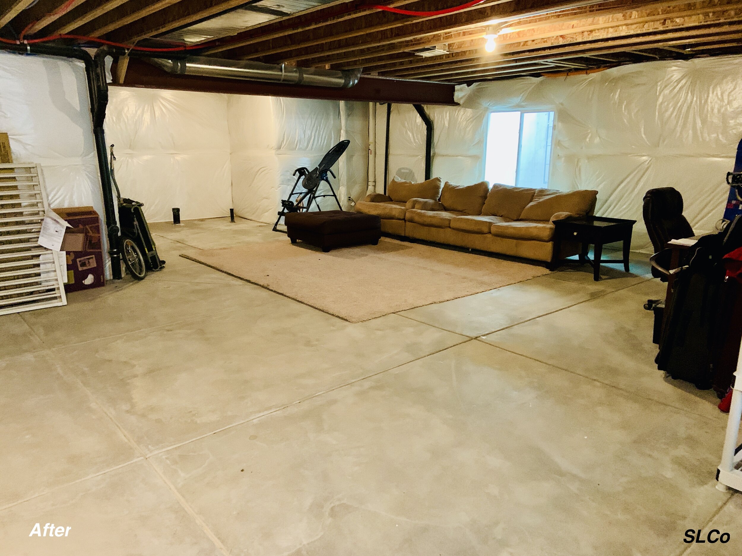 After photo of unfinished basement with a carpet in front of a couch and clear floor