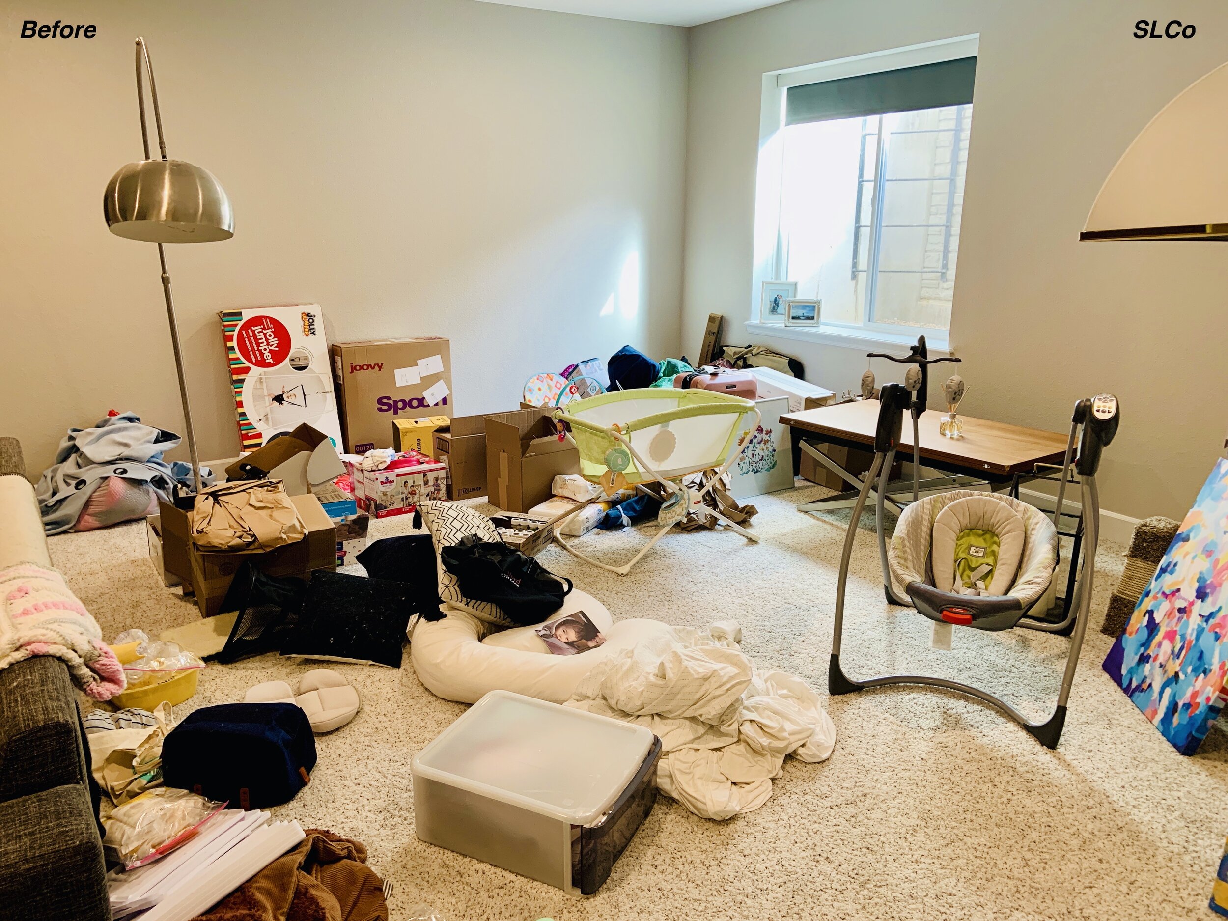 Before photo of large room with pillows, baby items, and other household items filling the whole room.