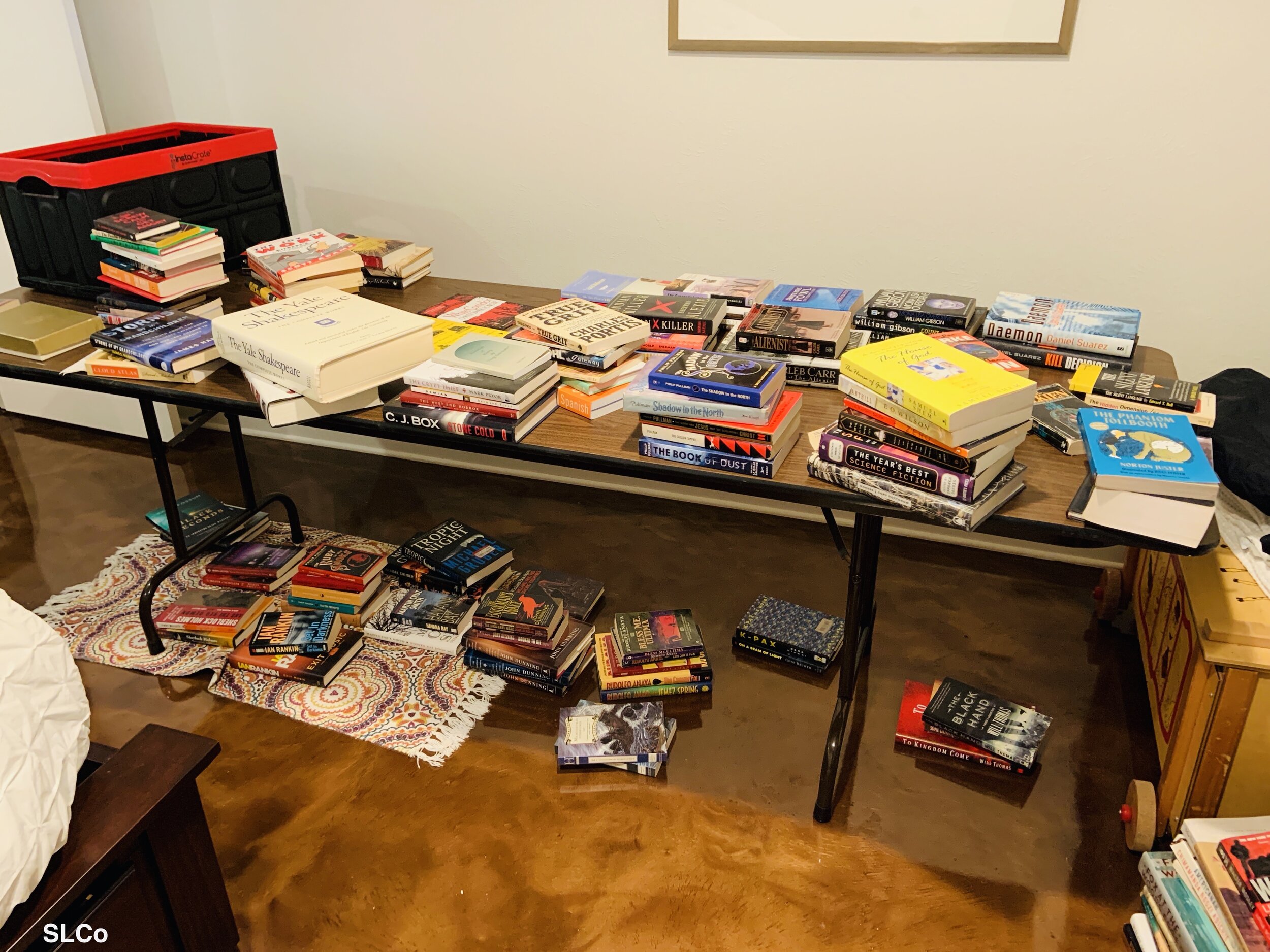 Table against wall filled with stacked books unorganized