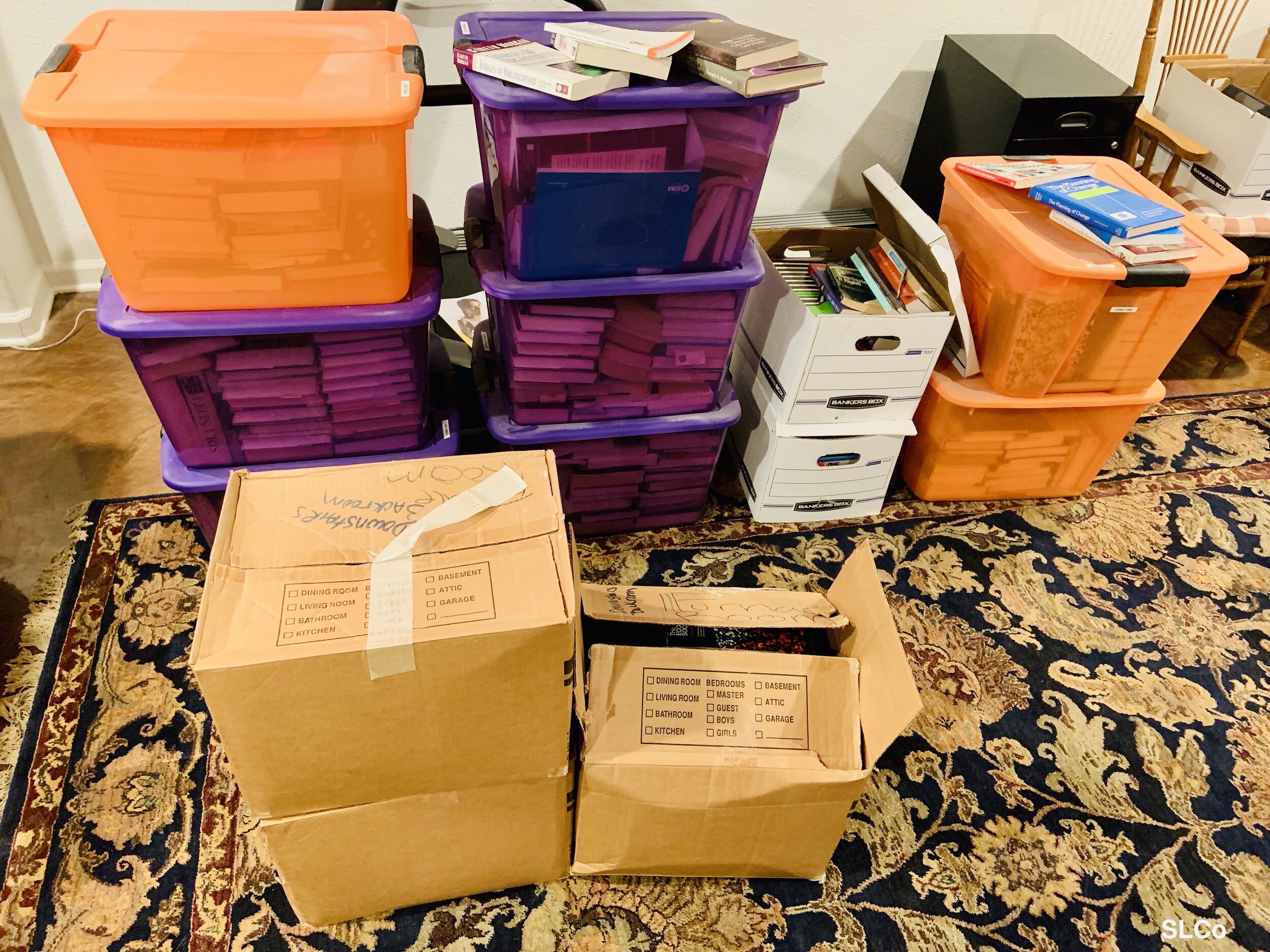 Purple and orange container bins stacked on floor filled with books