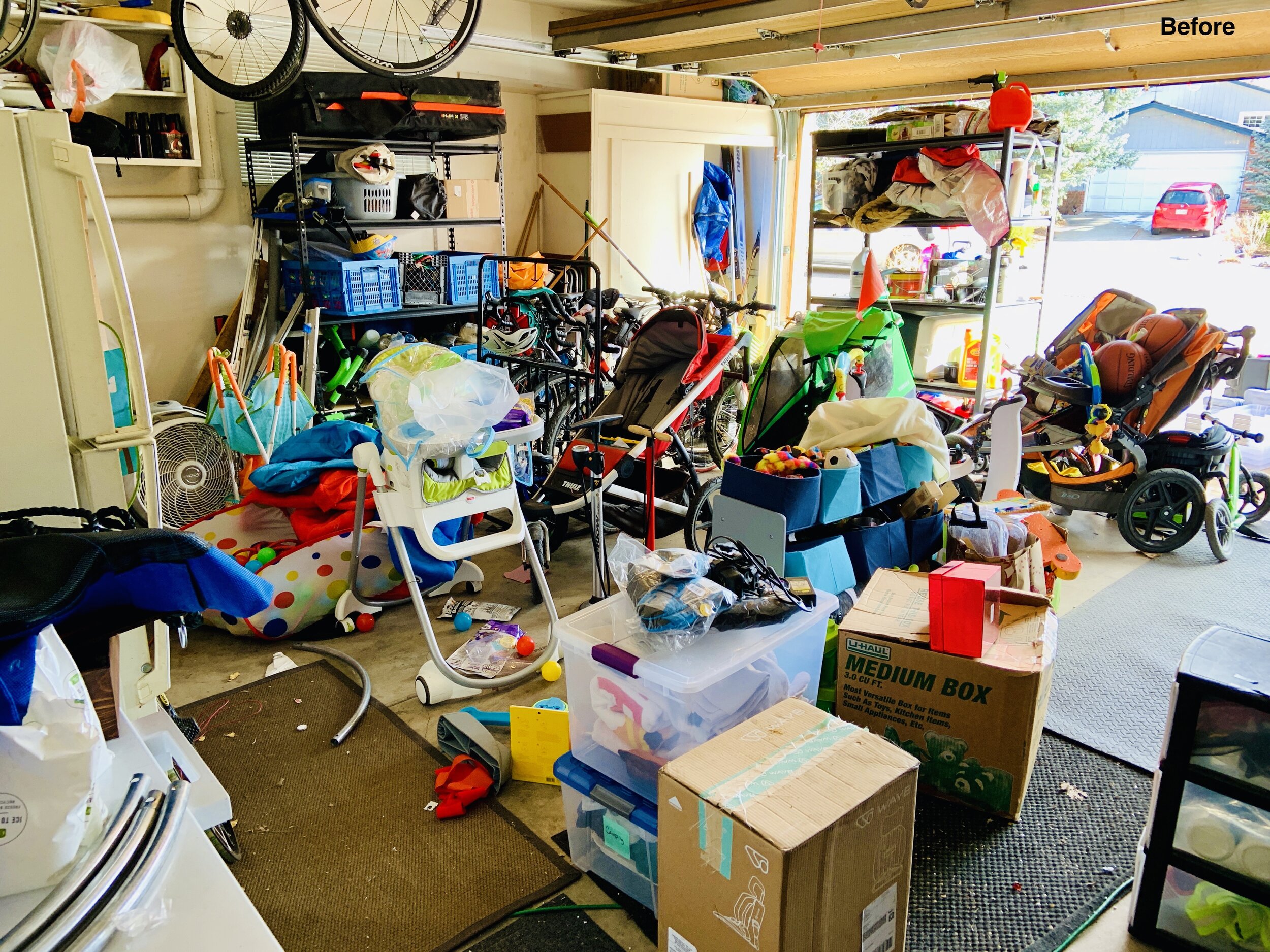 Before photo of garage stacked about 3 ft with strollers, babe items, and moving boxes, unwalkable.