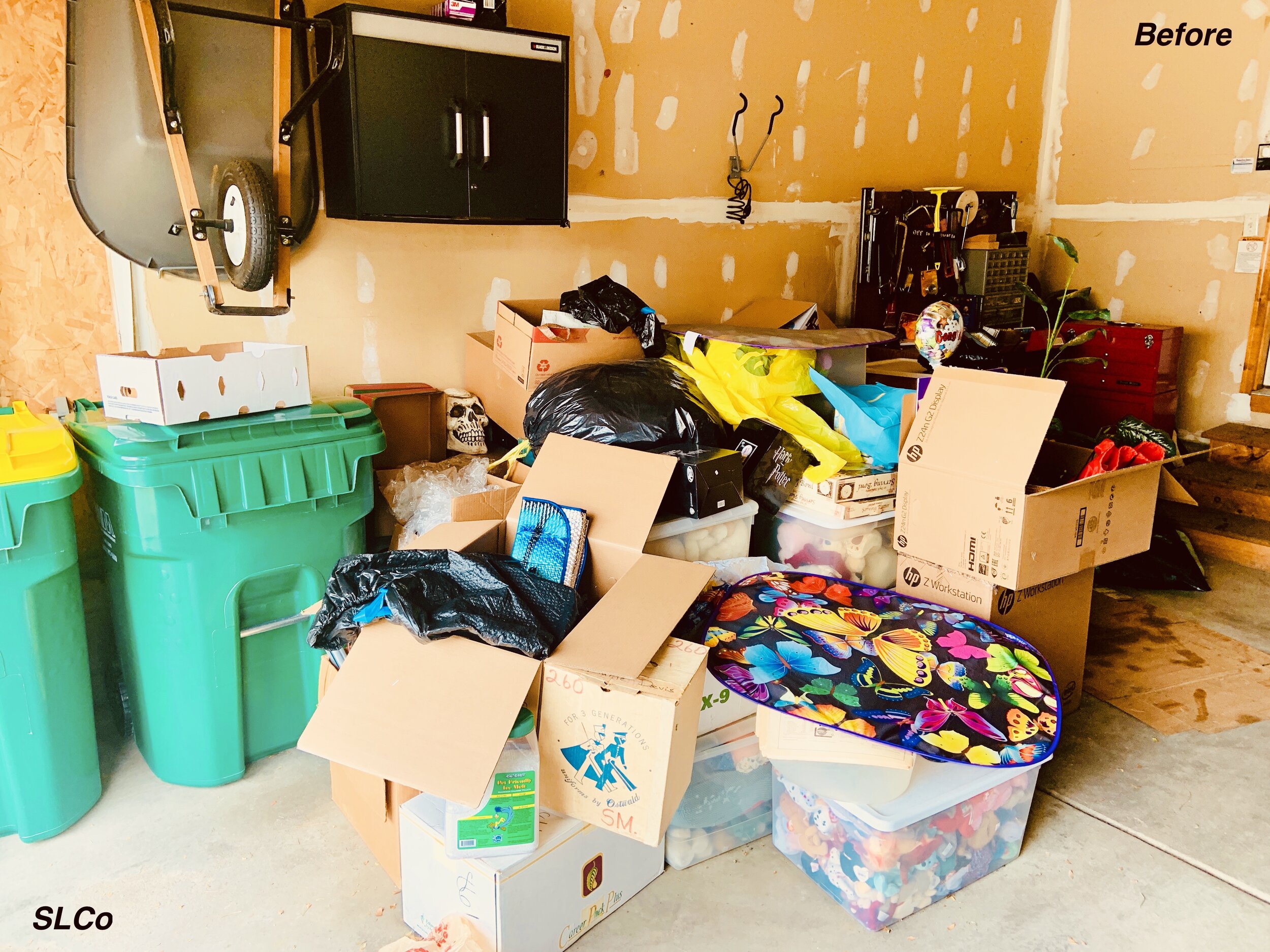 Before photo of garage with green trash bins and containers overflowing and moving boxes stacked on top with random items.