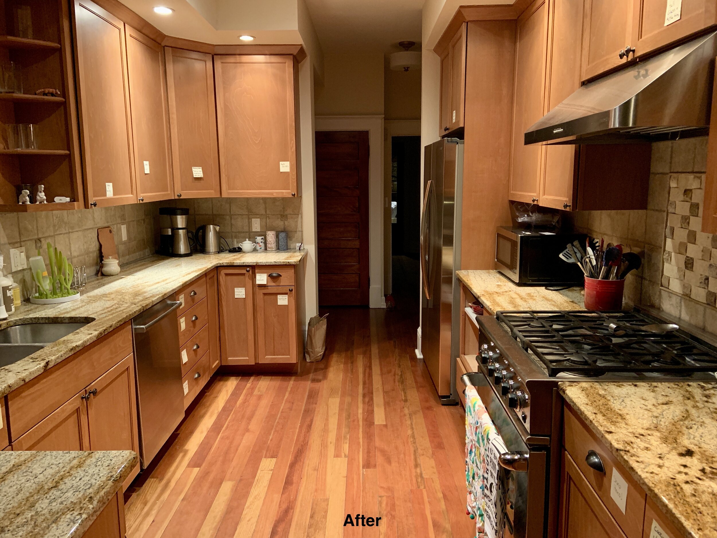 After photo of wooden floor and wood cabinet kitchen compeltely clean with post it notes labeled on every cabinet. Counter clean.