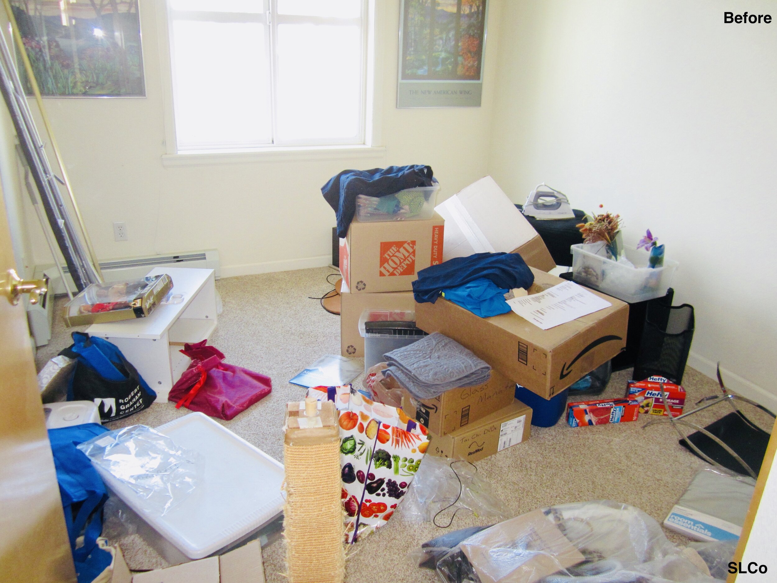 Room with white calls with moving boxes and containers in a mess on floor
