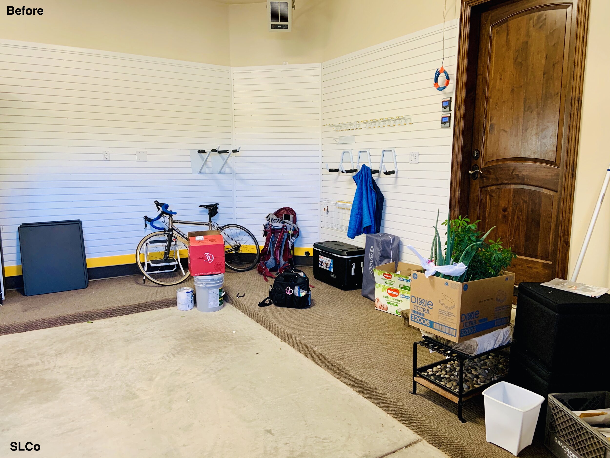 Garage with bike on floor, hanging aparatuses on wall not being used, and items on floor leaning against wall