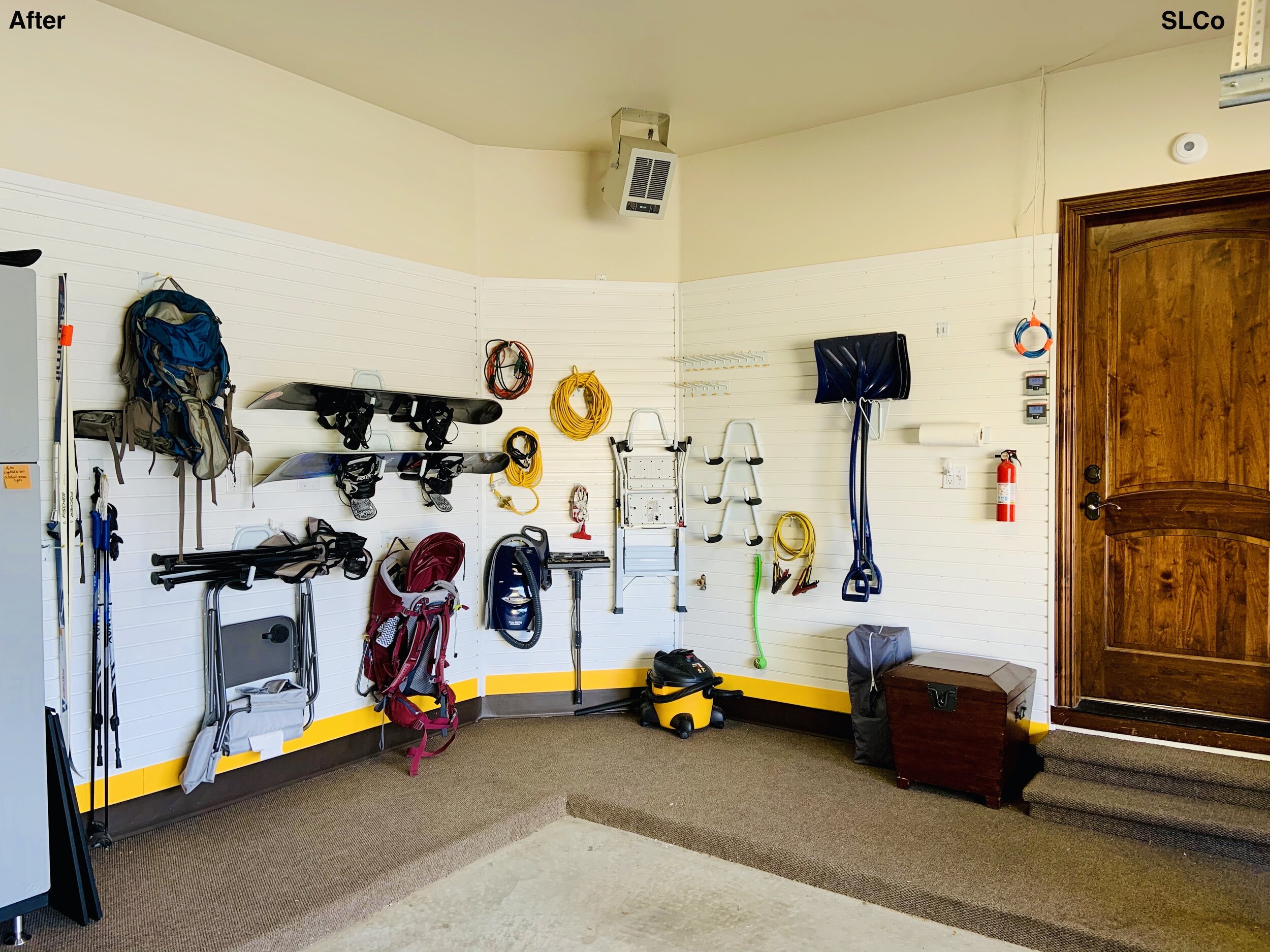 Clean garage with snowboards, bags, and chairs handing on wall, floor clear