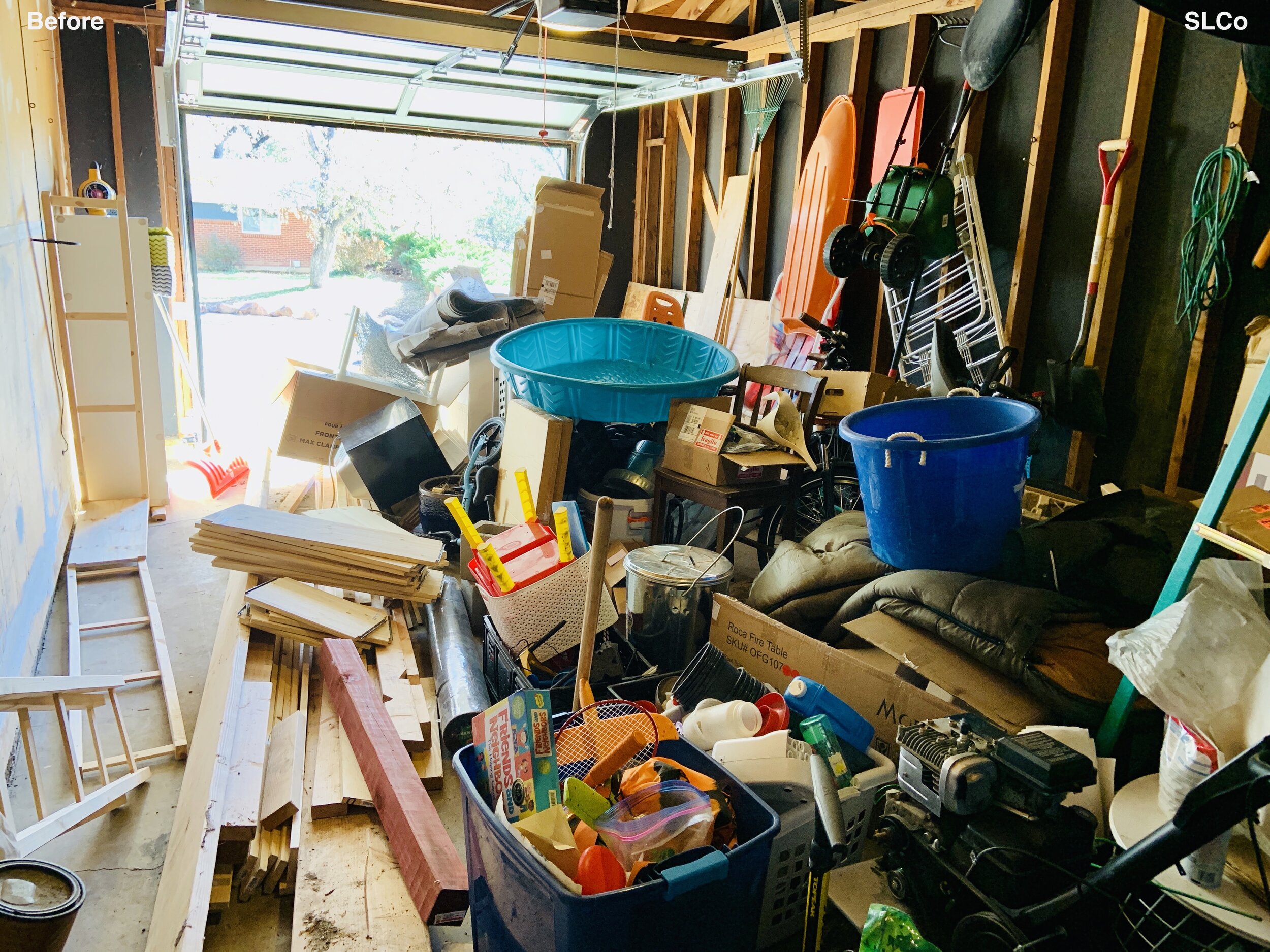 Before photo of unusable garage filled with wood and bins, unwalkable