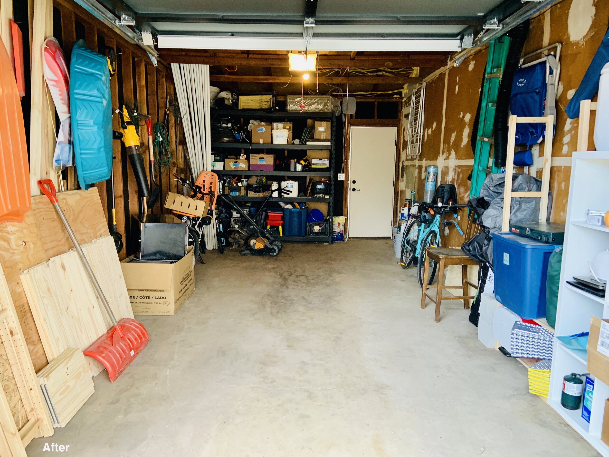 After photo of garage with wood leaning against wall, items hanging from walls, and floor clear and usable view from garage door