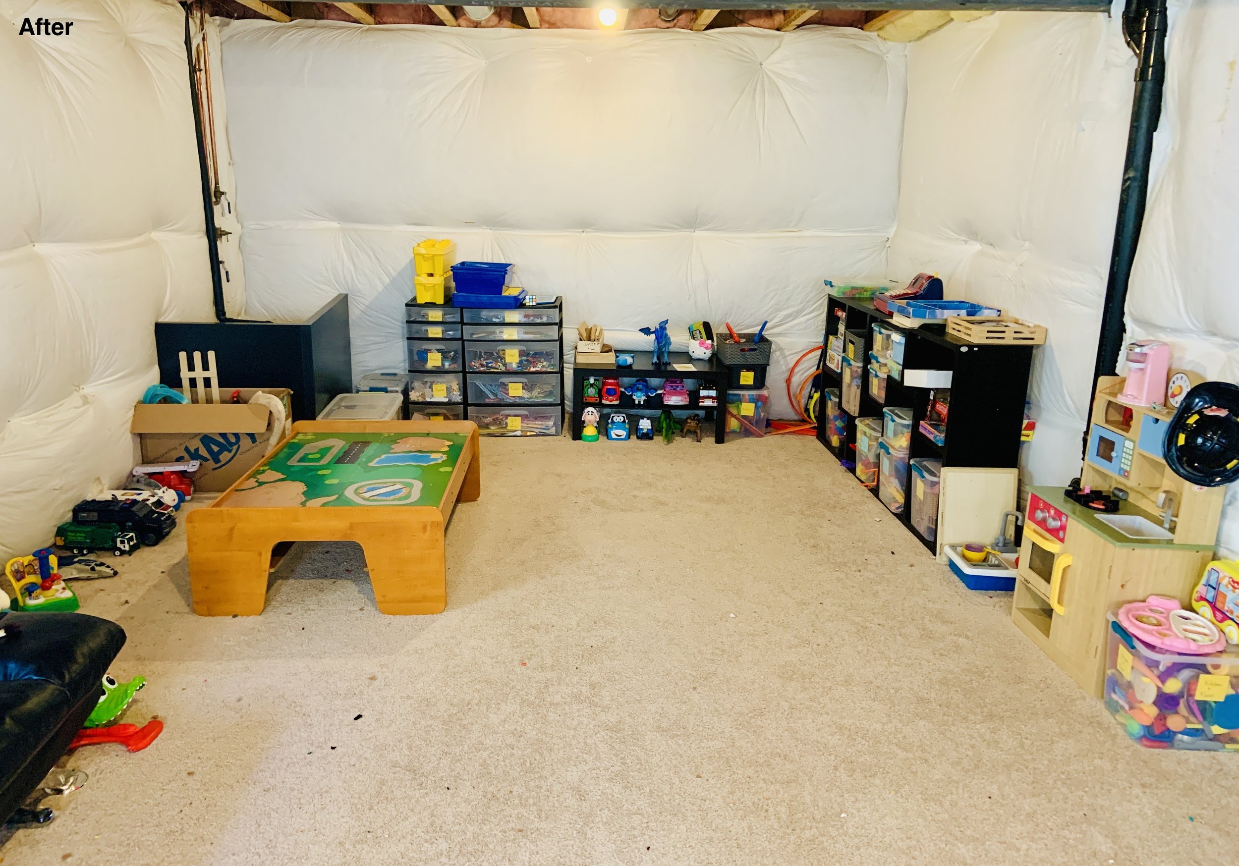 After photo of playroom with black shelving units with toys nearly organized and drawers labeled, floor is open and useable.
