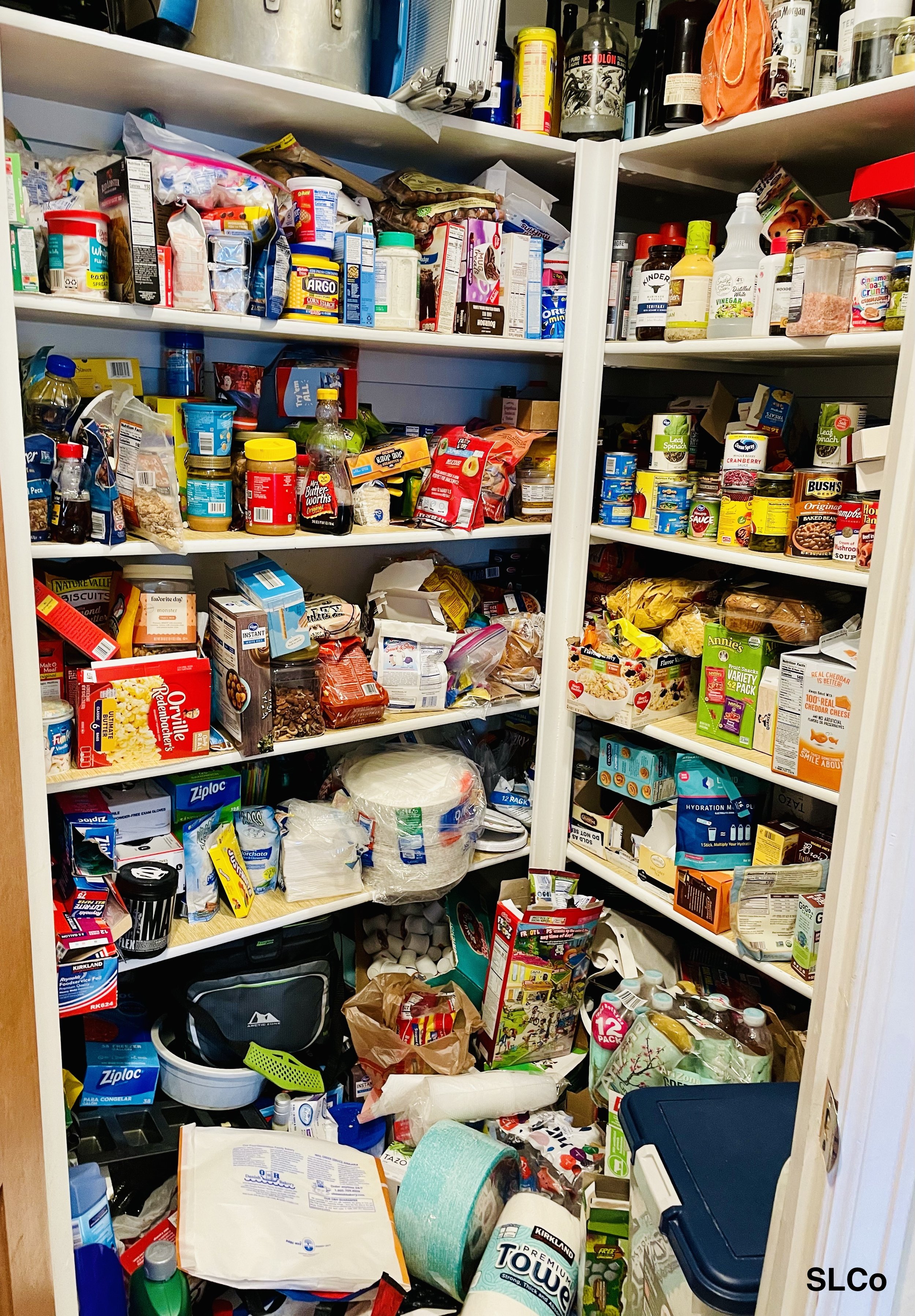 Large quarter pantry with items on floor and shelves overflowing