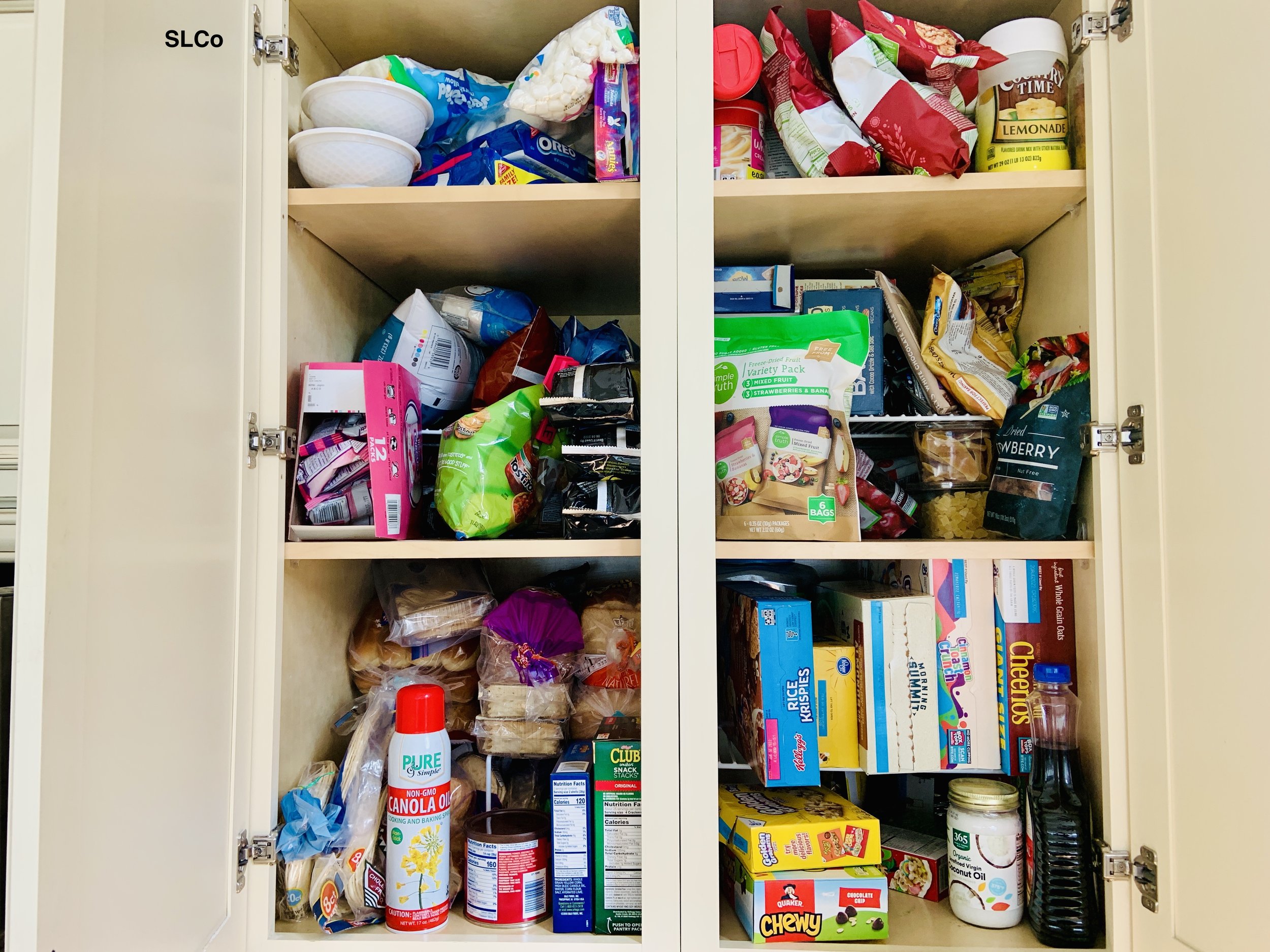Small cabinet pantry stacked with cereal, flour, and other kitchen items.