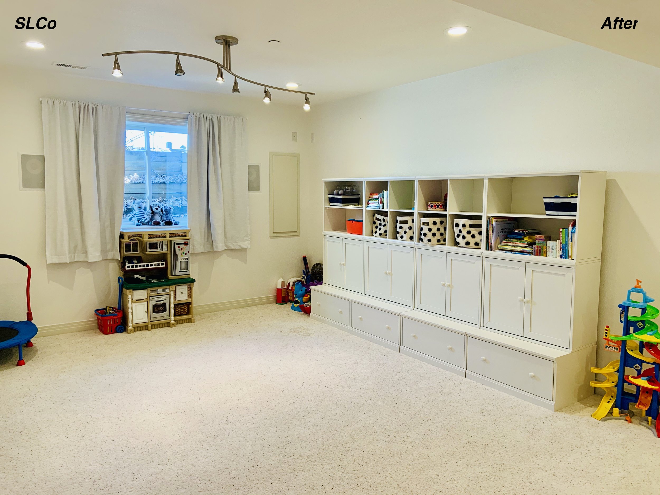 After photo of large playroom with carpet clean, nothing on the floor, and items in the cabinets and shelves.