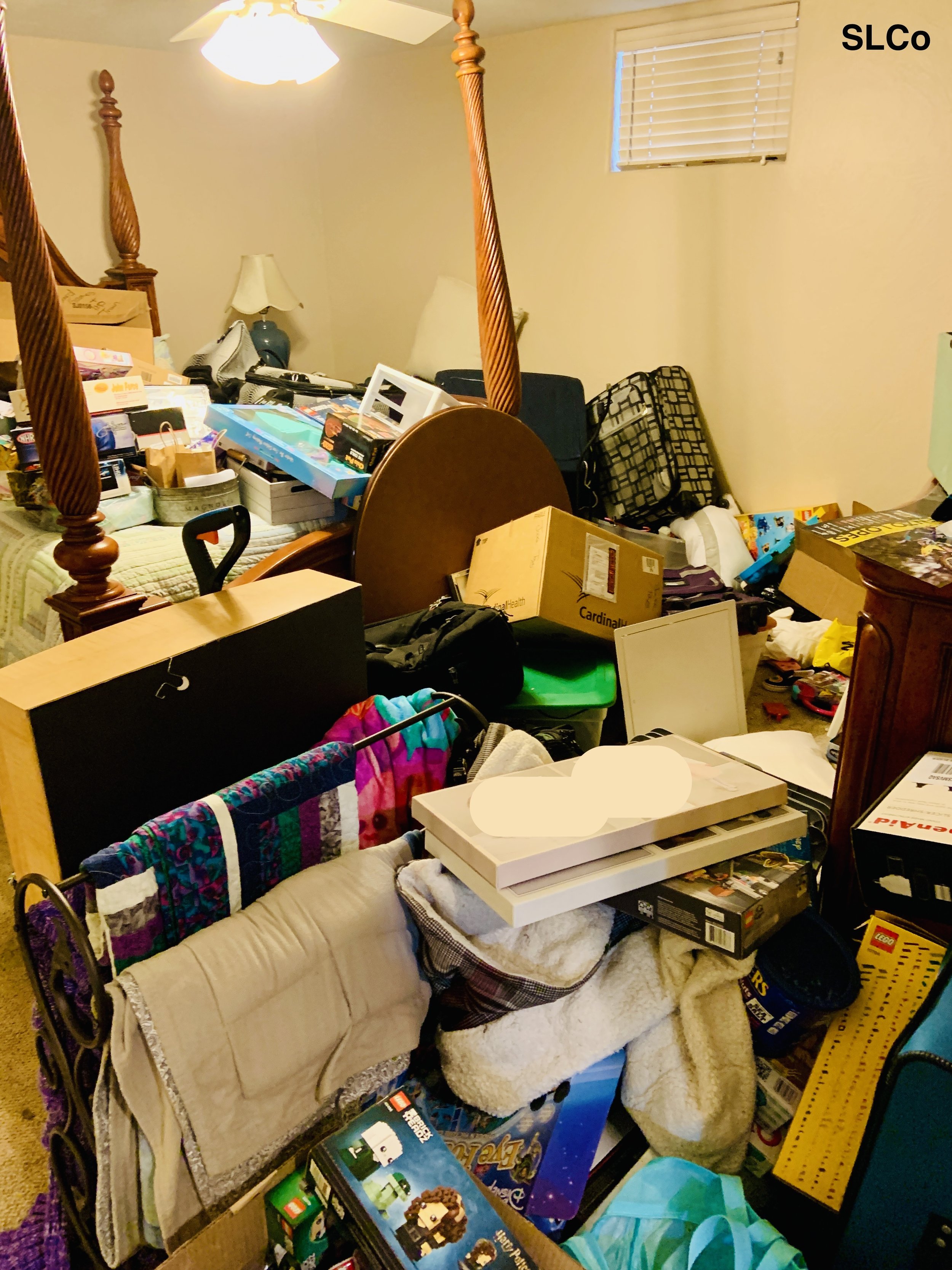 Before  photo of bedroom with large bed with wooden posts with items on bed and floor