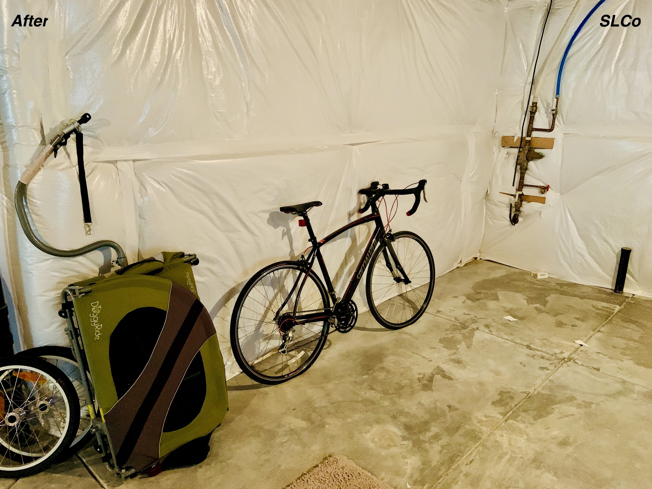 After photo of unfinished basement with bike against wall and floor clear