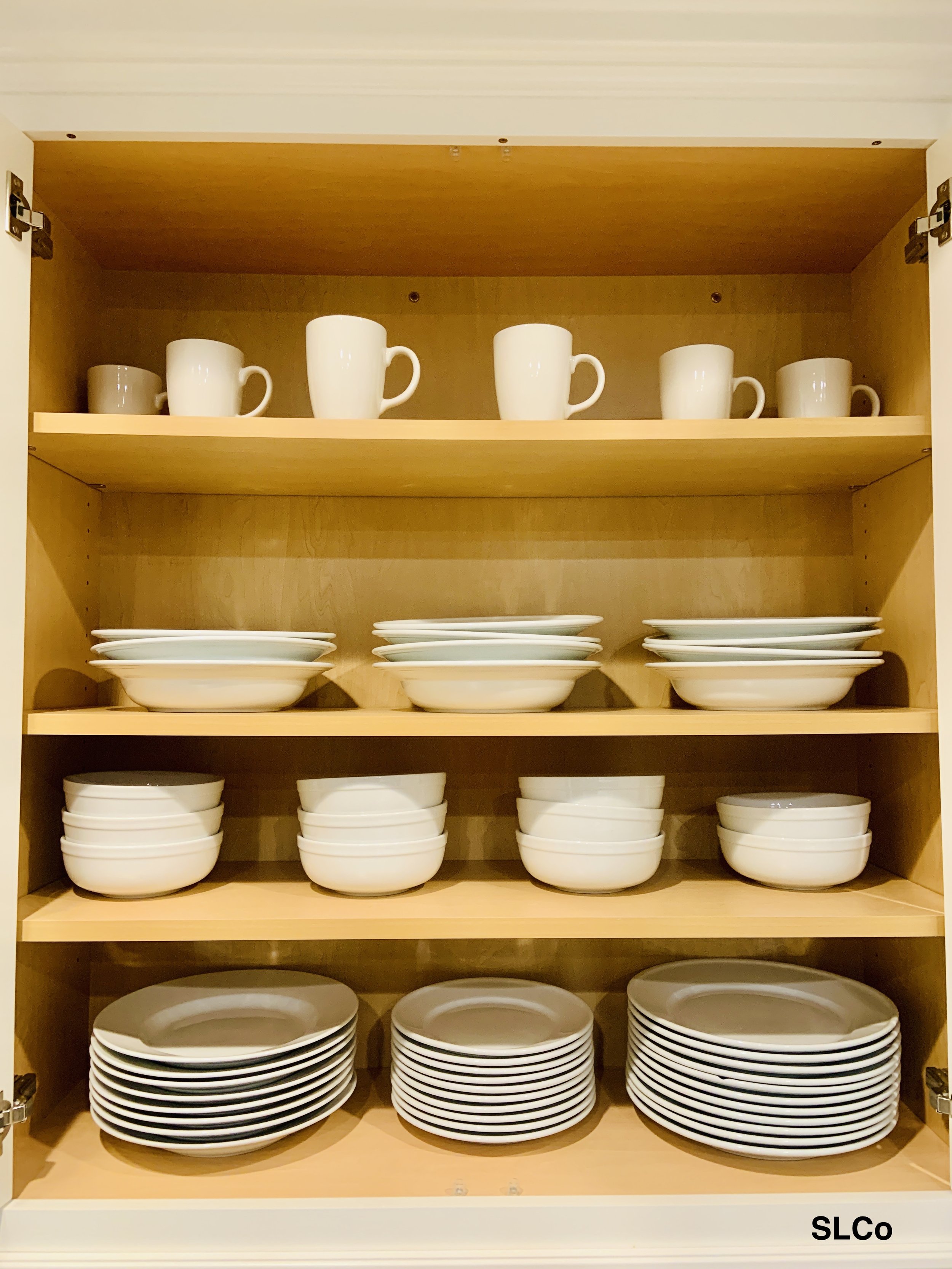 4 wooden shelves in a cabinet with bowls and mugs places spaced apart