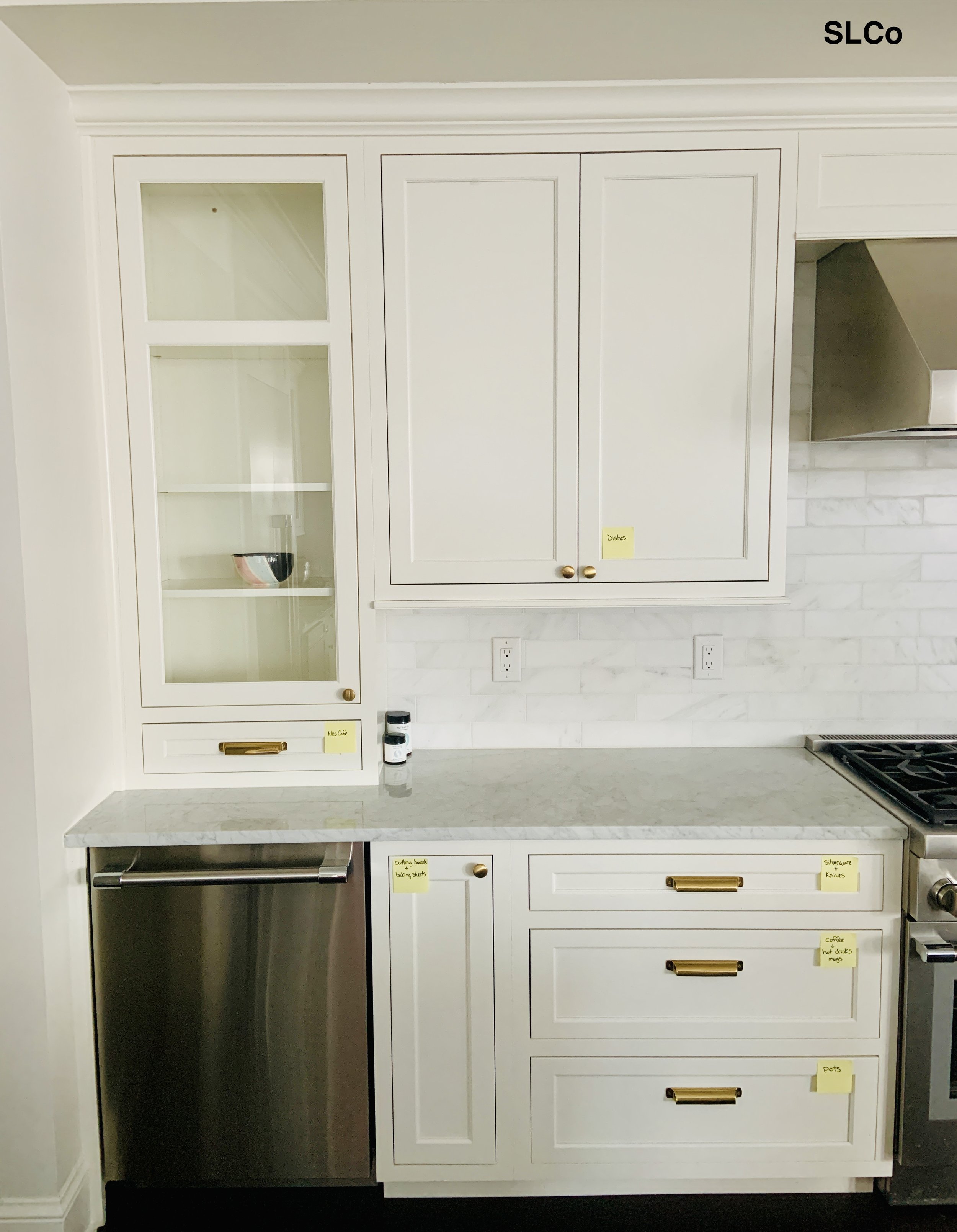 Kitchen corner with white cabinets and granite countertop, all clean and  yellow post its on the corners of drawers and cabinets