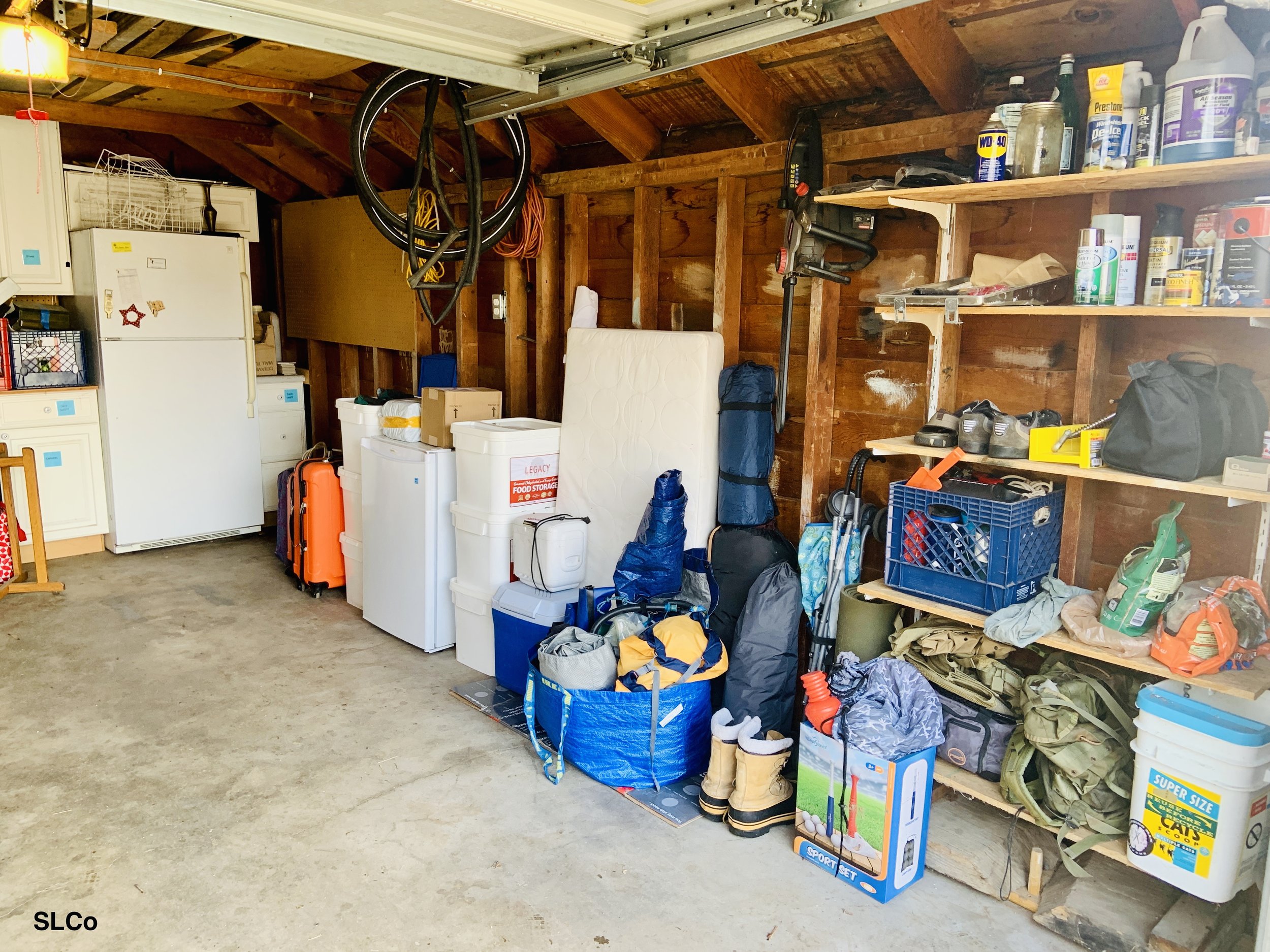 After photo of garage with clear floor, facing the back of the garage, items neatly placed against wall and fridge on the back wall