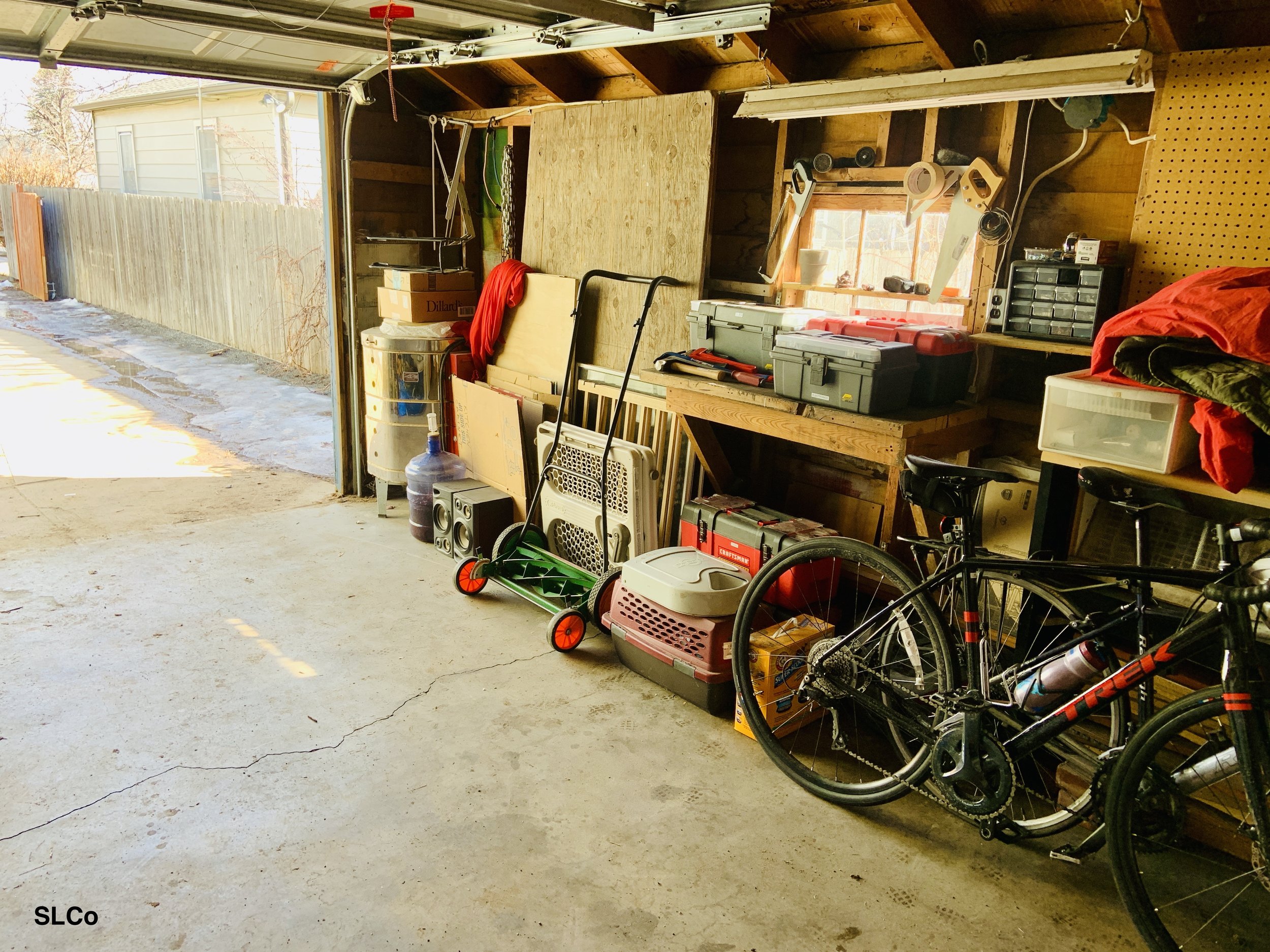 After photo of garage with clear floor, facing the garage door, items neatly placed against wall