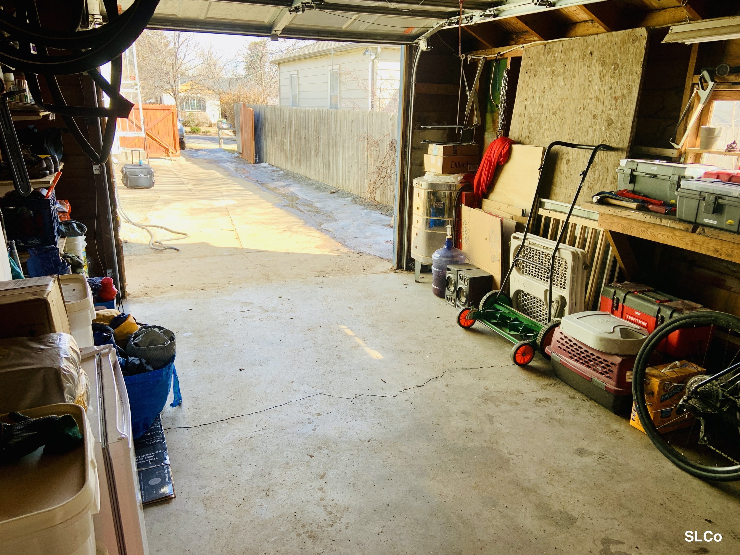 After photo of garage with clear floor, facing the garage door, items neatly placed against wall