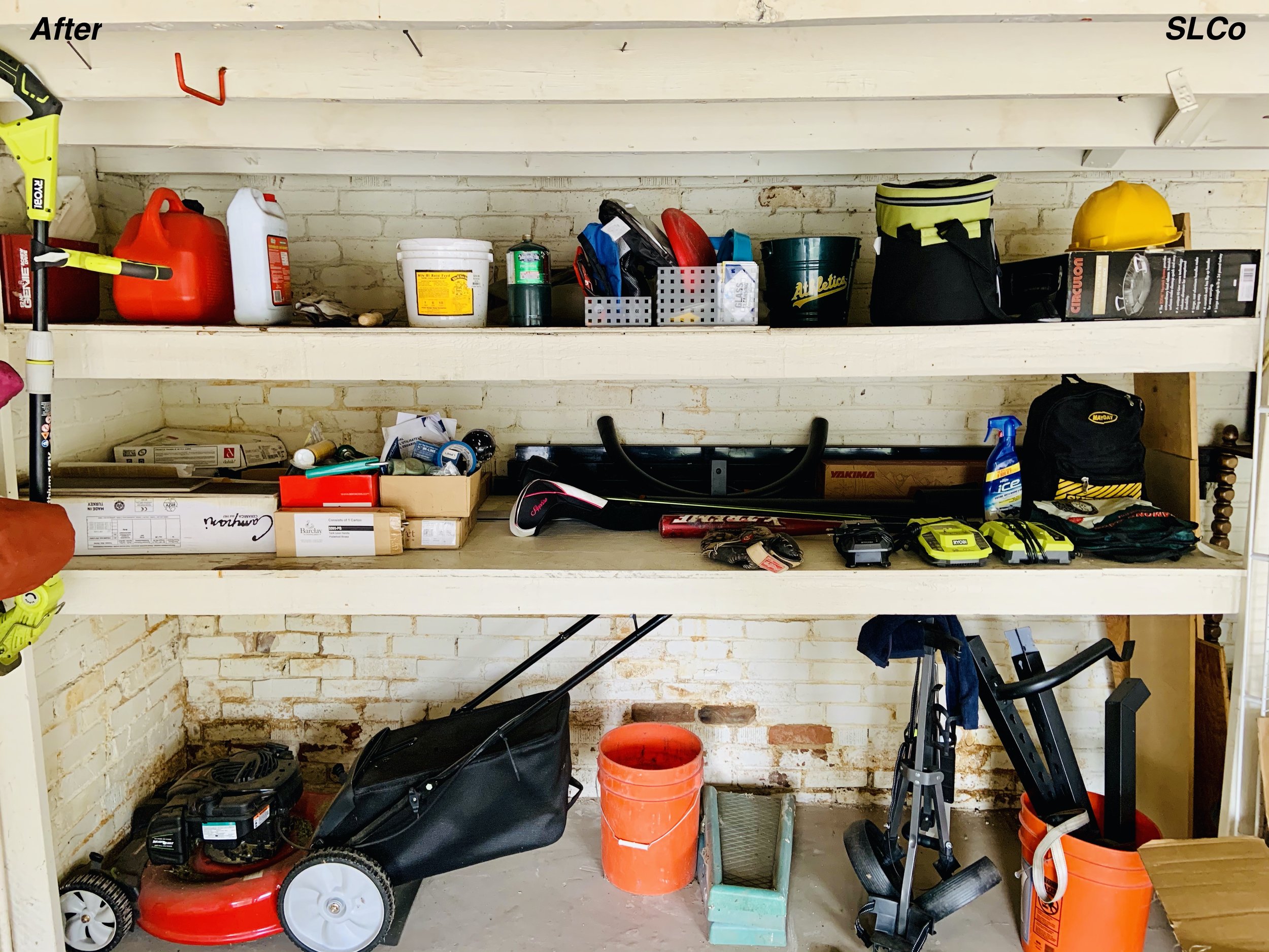 Close up after photo of built in shelves that are long with less pain, no items stacked on floor, lawnmower there and other items nearly placed.