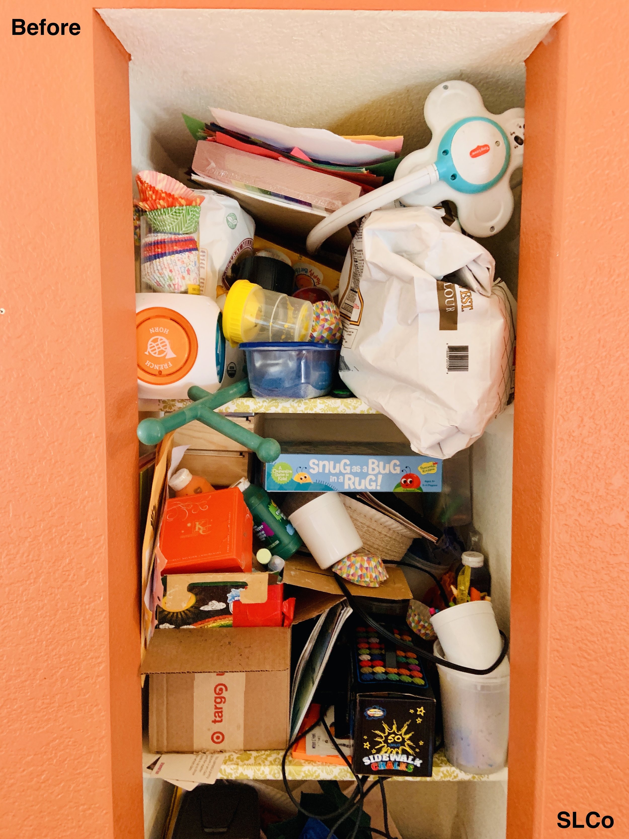 Before photo of kitchen cabinet overflowing with paint and games