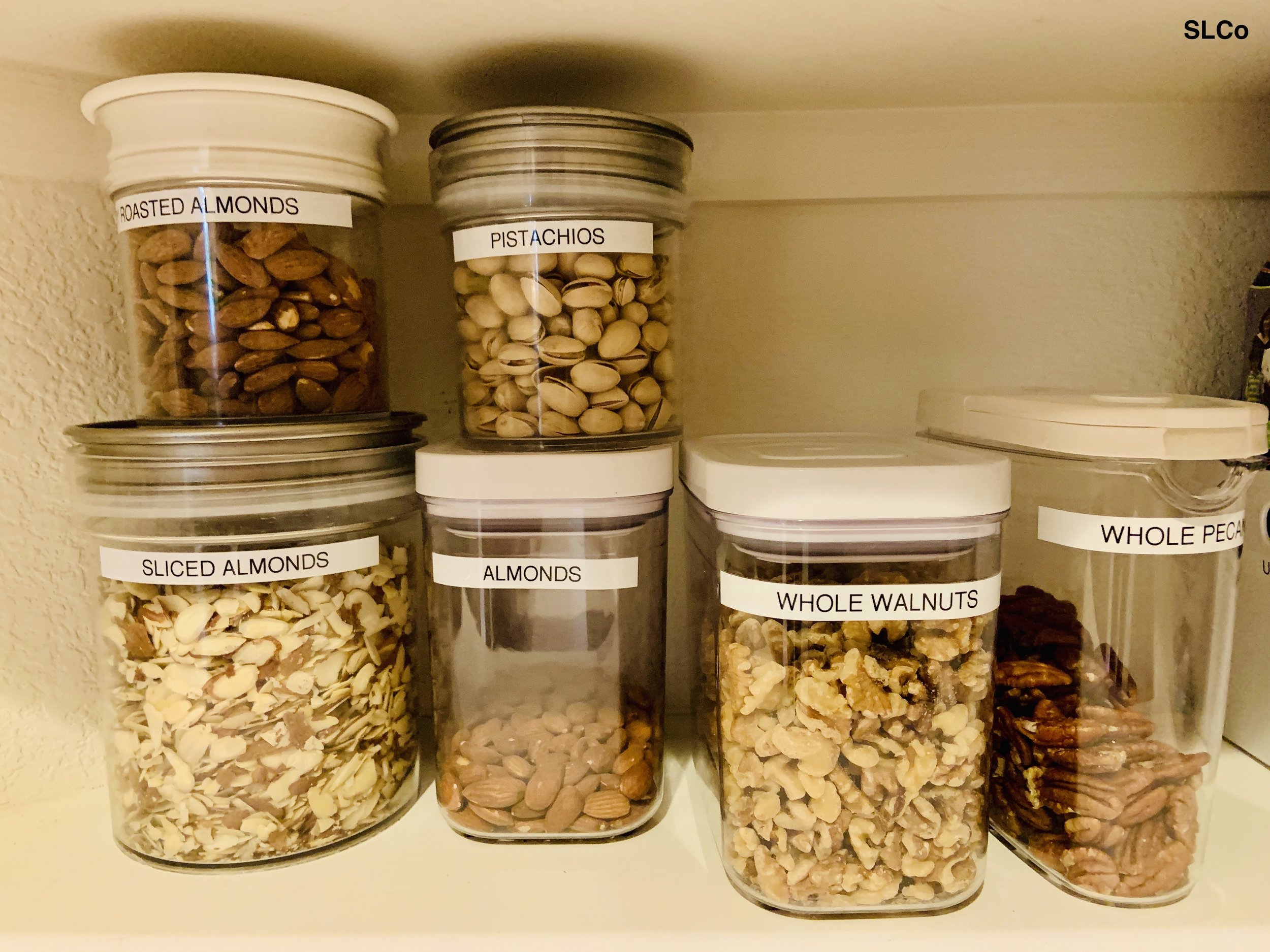 Kitchen shelf with clear plastic containers with labels for nuts