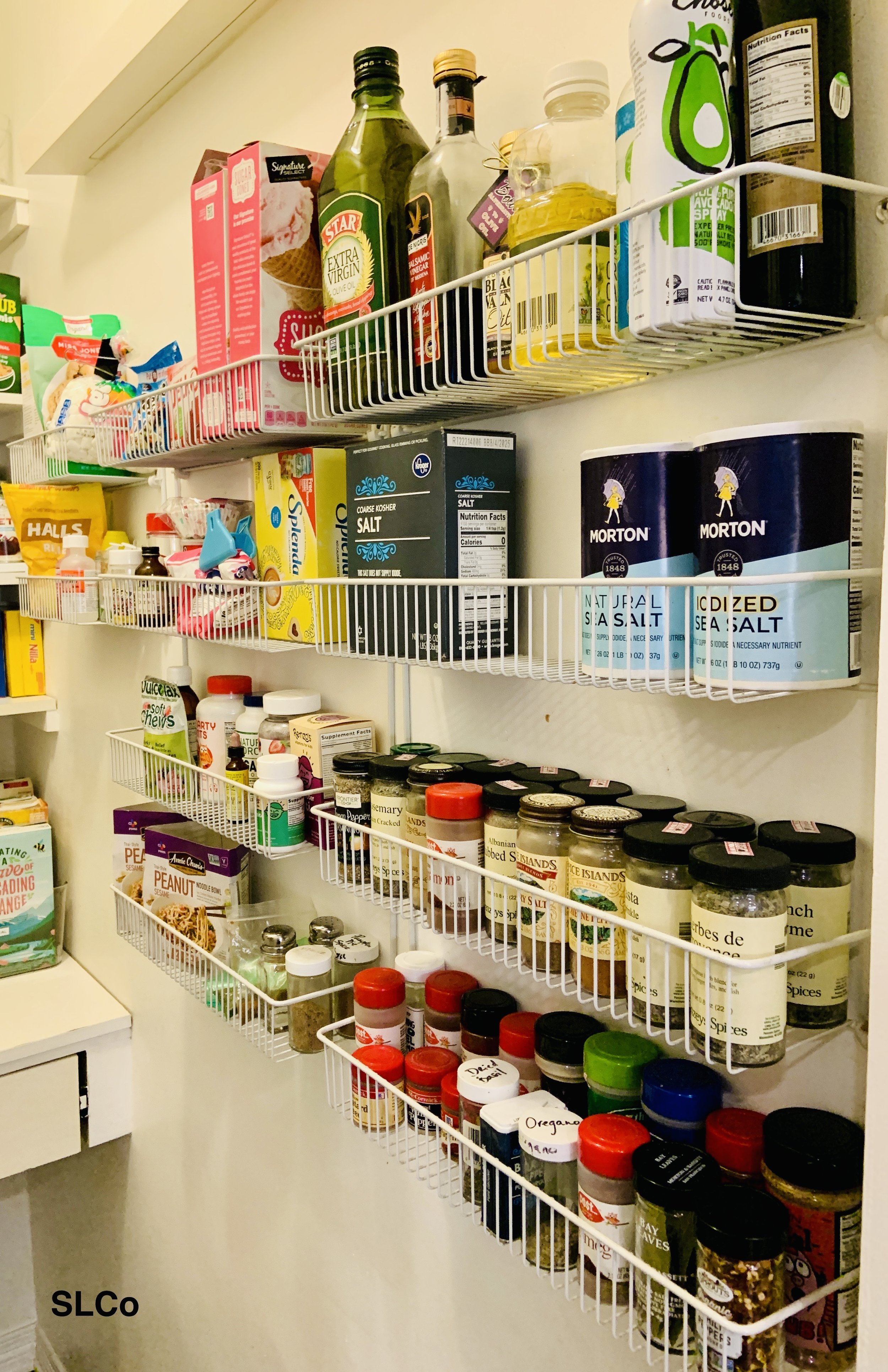 White small wired shelves on wall with spices together and items in their own homes.