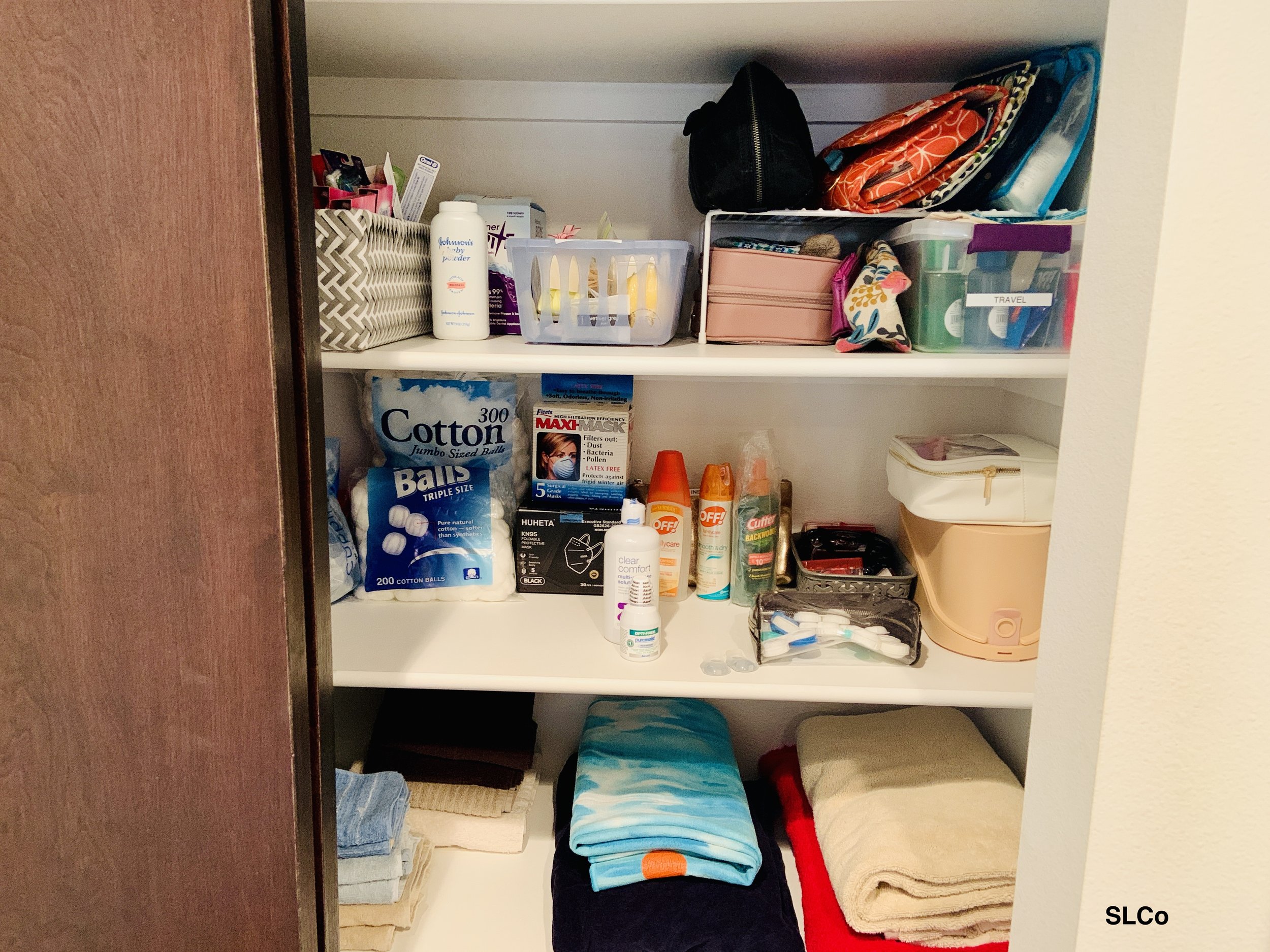 After photo of hallway closet with three shelves with the top two shelves with beauty products in organized and labeled containers and the bottom shelf with folded and organized towels.