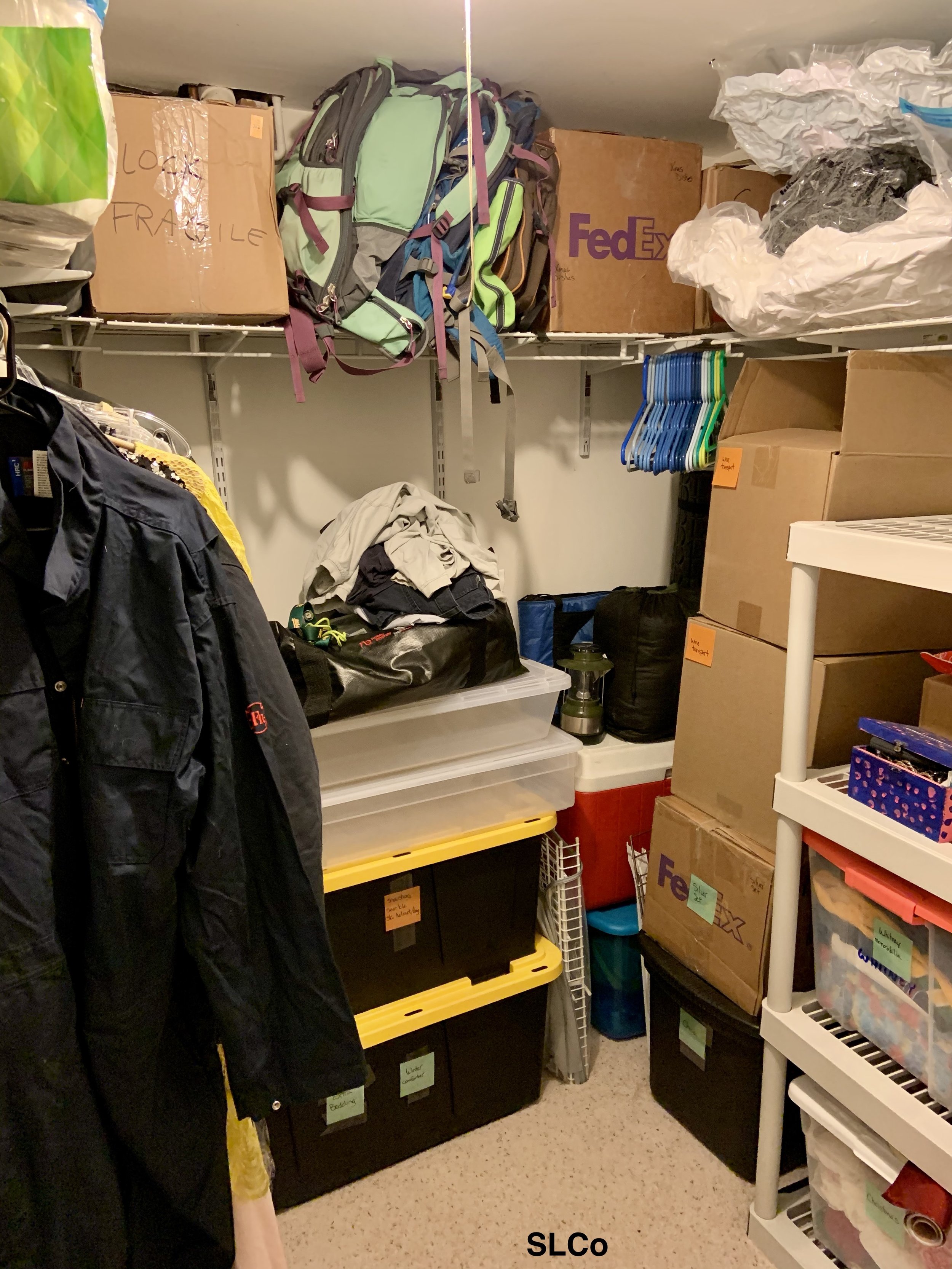 After photo of closet with white shelves, boxes stacked neatly and labeled, and clothes hanging.