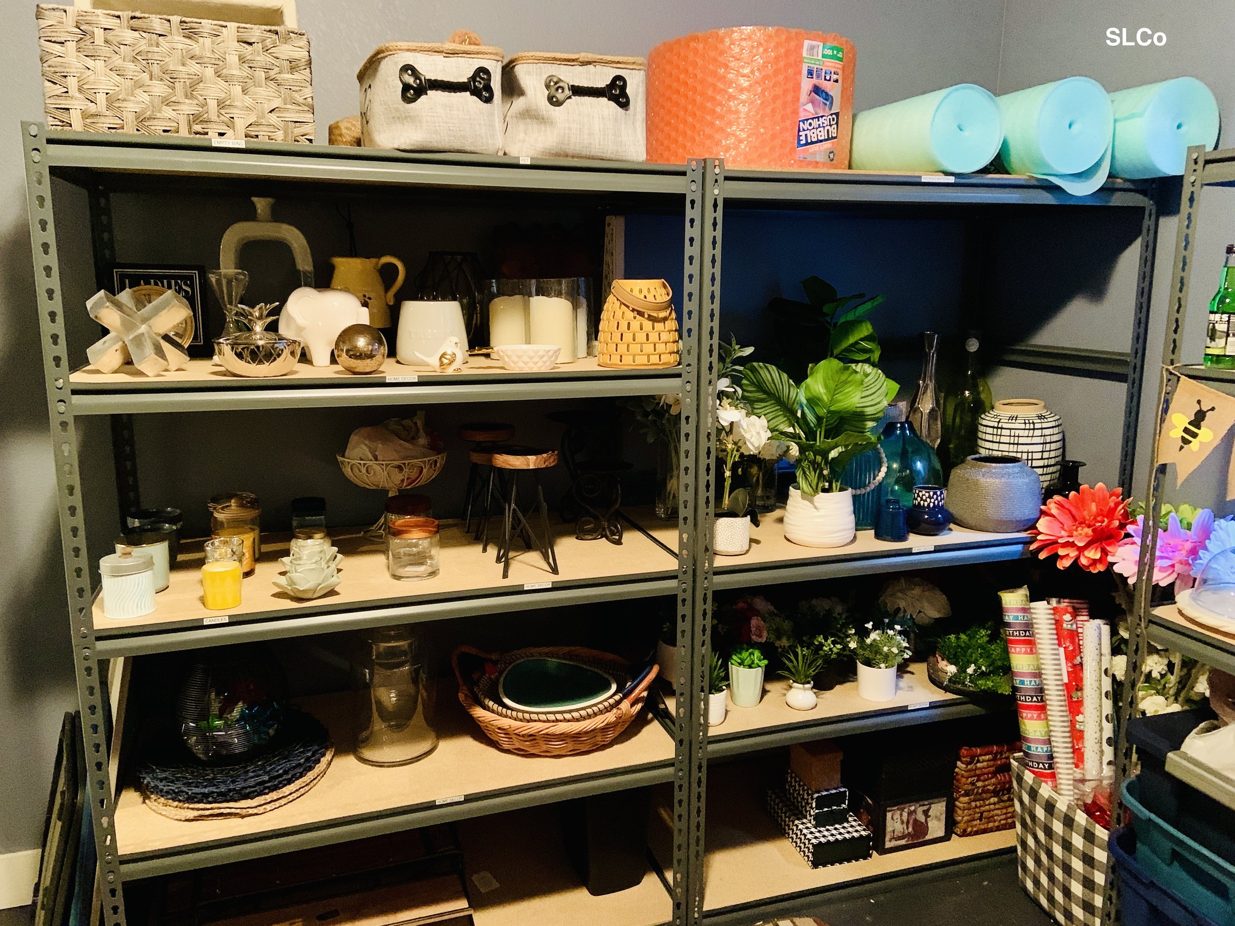 Close up of metal shelving unit with knick knacks, succulents, and miscellaneous items organized
