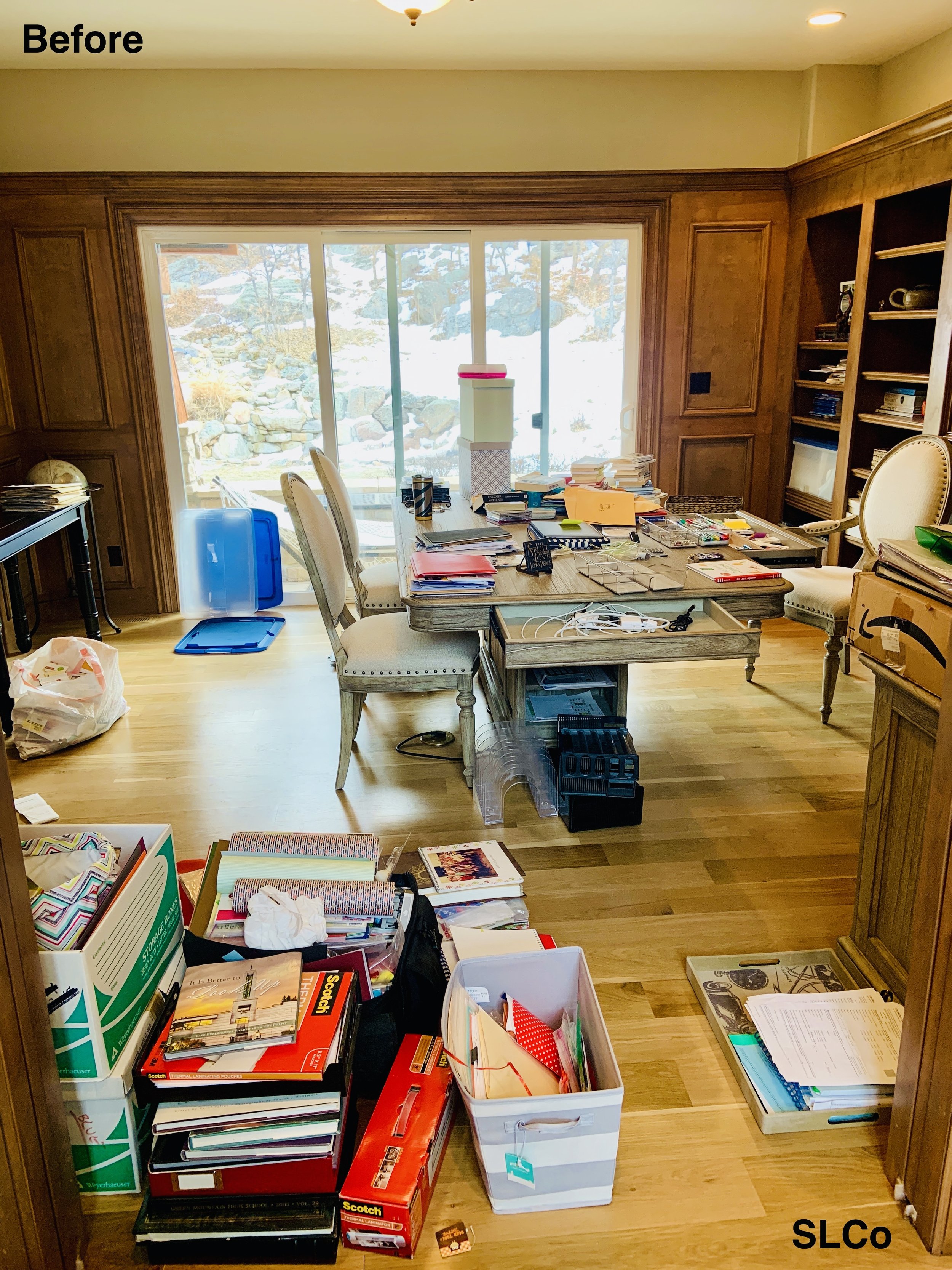 Before image of home office with stacks of books on the floor and desk cluttered and filled with items.