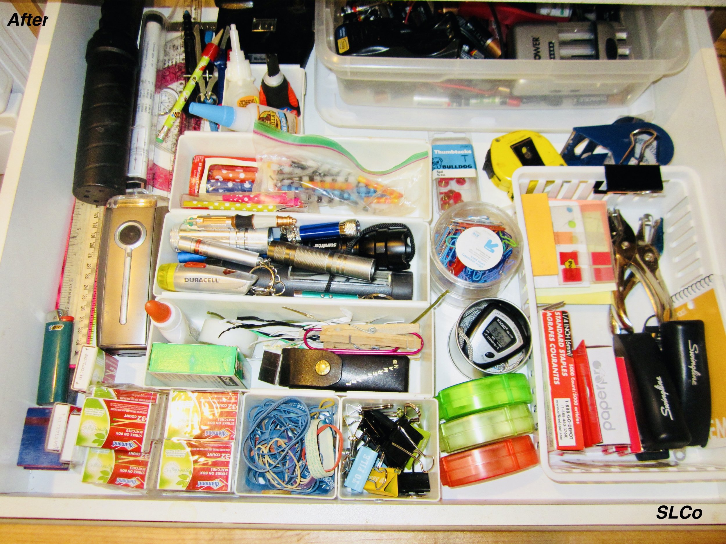 After photo of large drawer with white containers organizing items into staples, rubberbands, pens, and more in an organized manner.