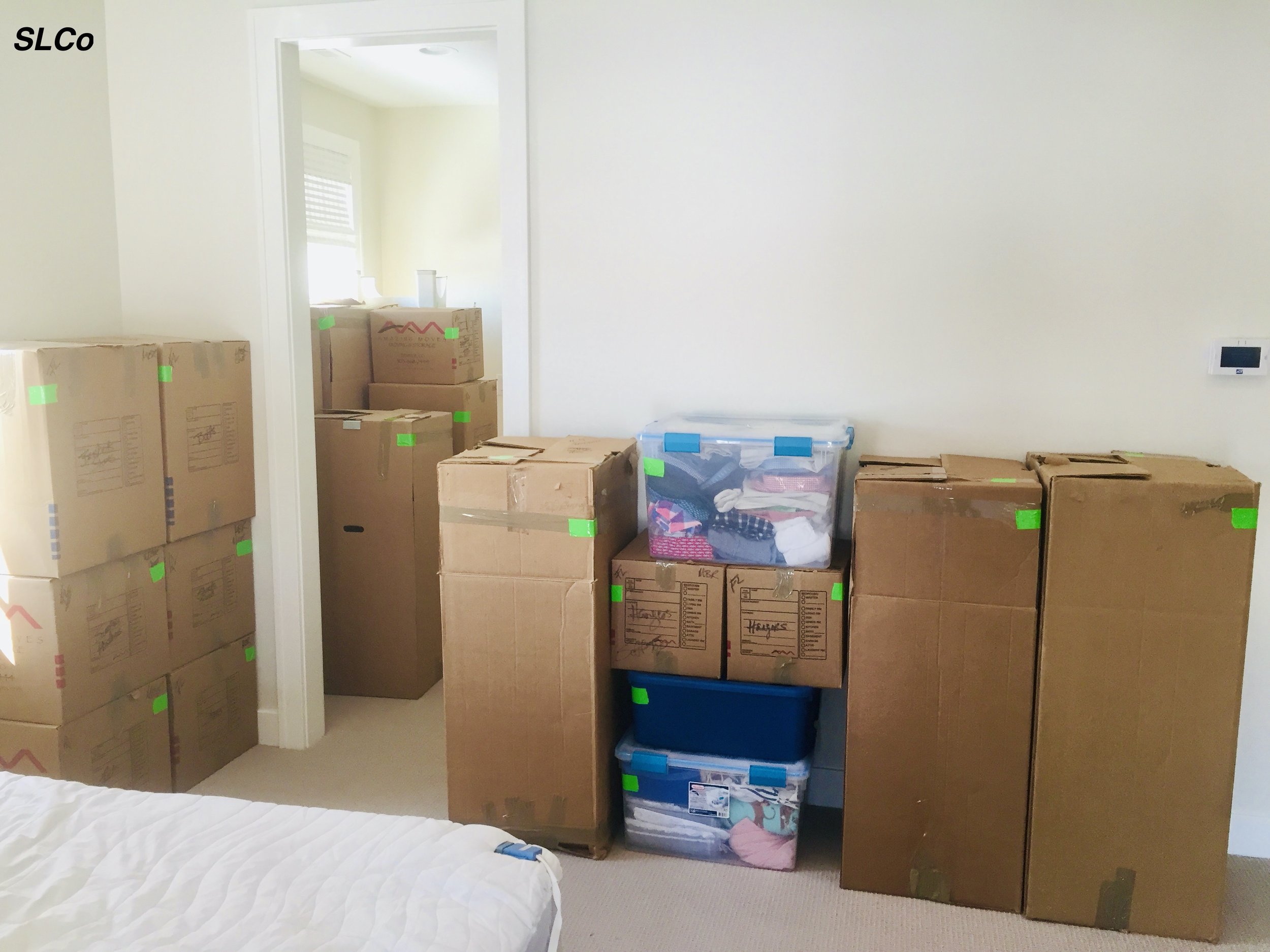 Bedroom with boxes packed against a wall and all boxes labeled.