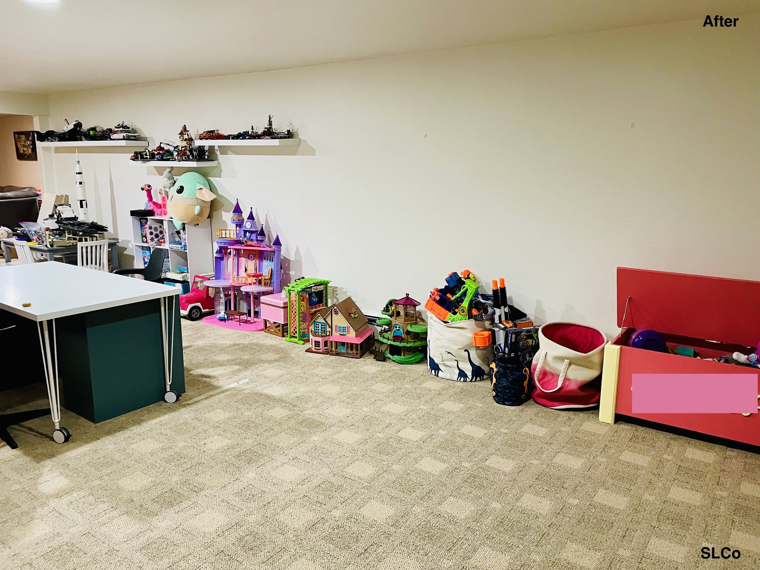 Large basement with floor clear, play table in the middle and toys lines against wall.