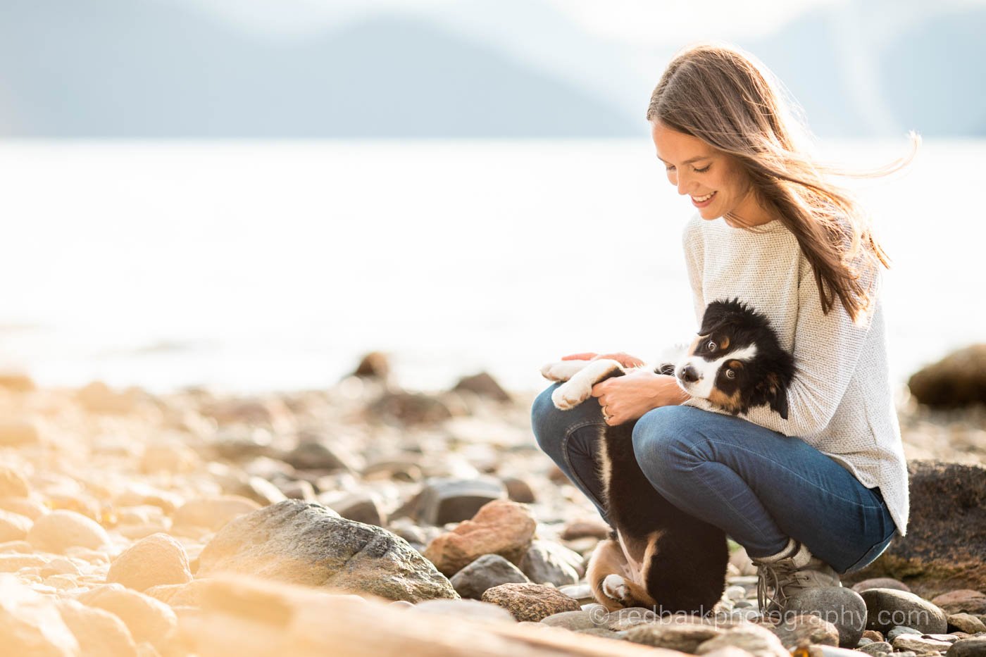 Bernese puppy and woman on beach