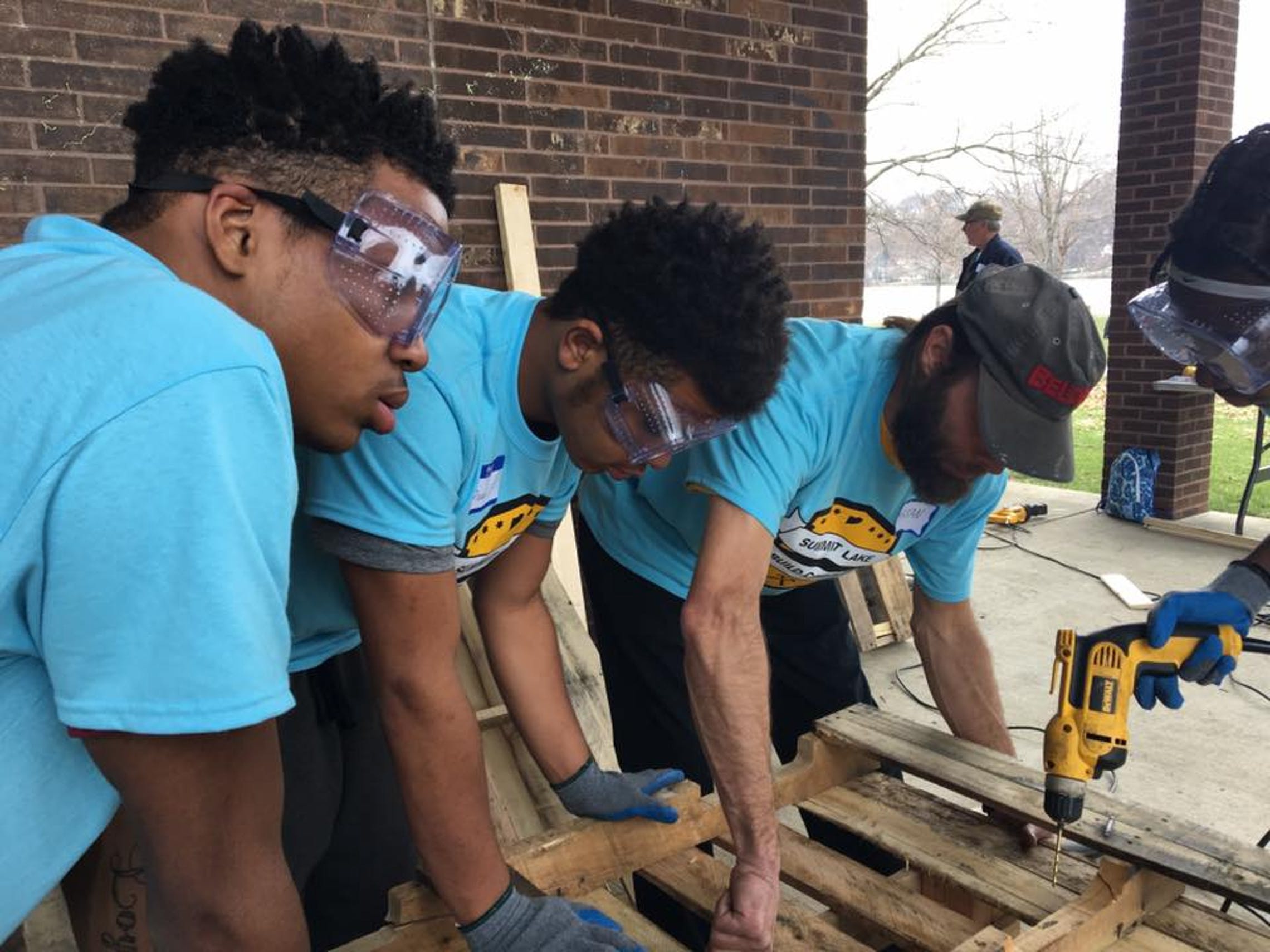 Jay (left), Divad and Ruth (far right) work with Build Corps mentor Bryan Huber on their bench.