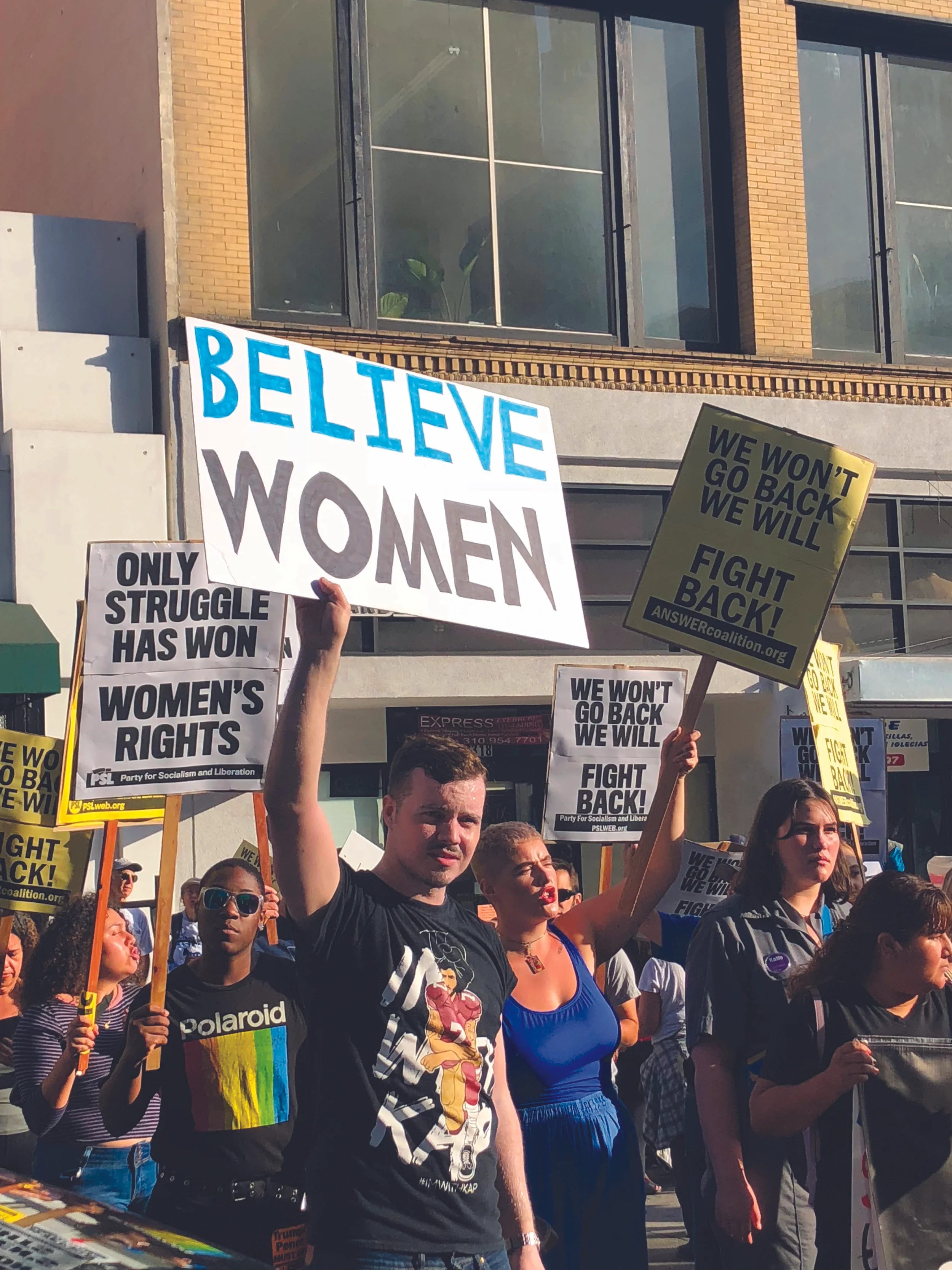 Protester holding "Believe Women" sign.