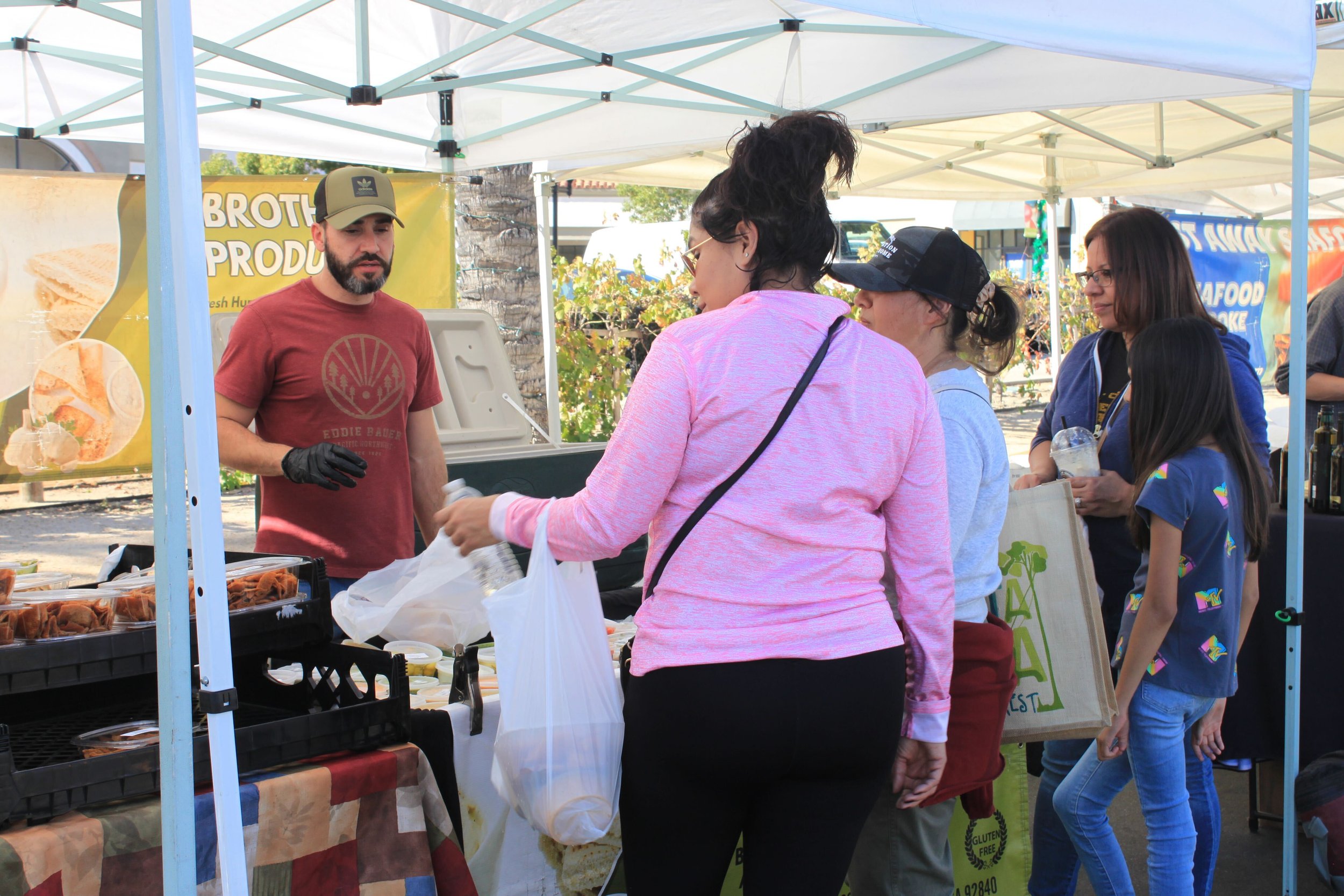  A family of four explores the abundance of fresh produce at the farmer's market, navigating the colorful array of fruits and vegetables to find the perfect ingredients for their wholesome journey. Photo by Jess Rodrigo 