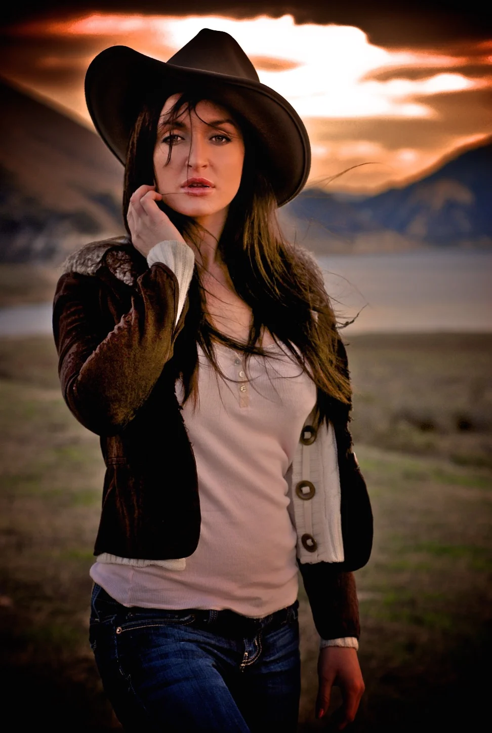 young sexy woman wearing Stetson cowboy cowgirl hat by a lake at sunset in Wyoming