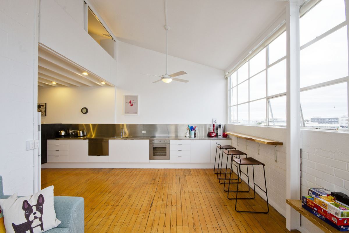 AFTER The kitchen has been moved into the main living area, giving life the the space. The mezzanine level was extended to provide another bedroom, with bi-folding shutters connecting to the living room below. A breakfast bar was added, perfect for enjoying the view of the city beyond.