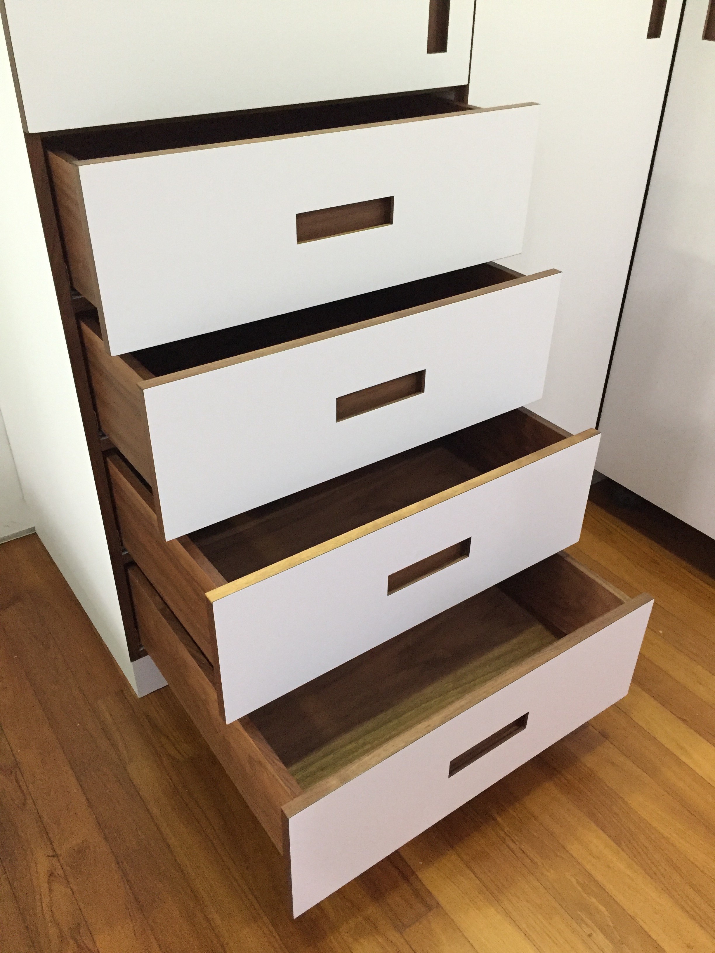 Exposed drawers with pocket handles in solid Walnut wood.