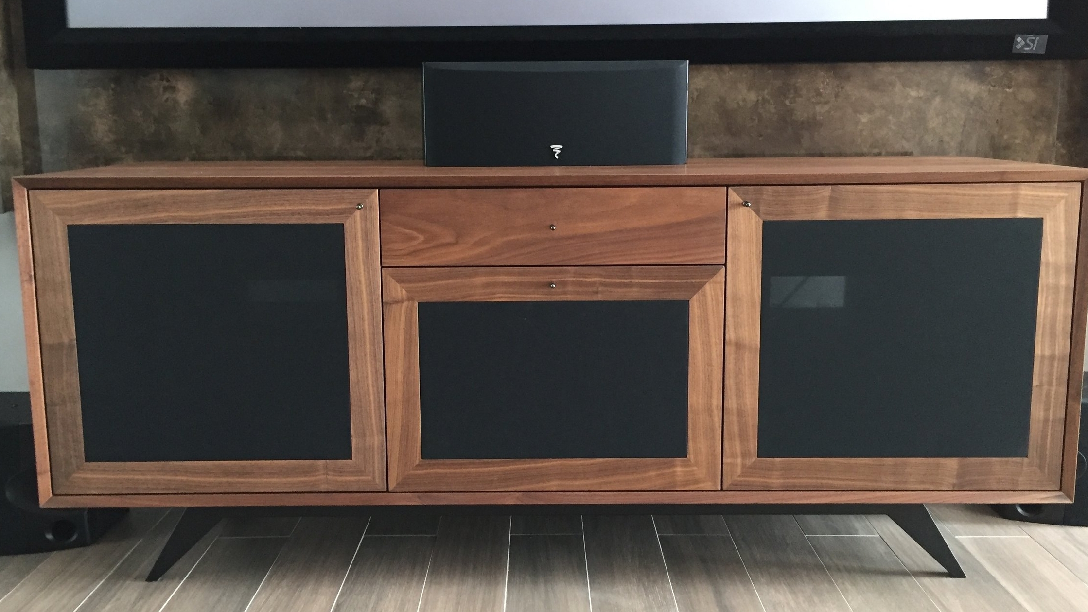 A sharp TV console built with Walnut veneer and black wire mesh for ventilation and remote controls to work without the need to open up the cabinet doors.