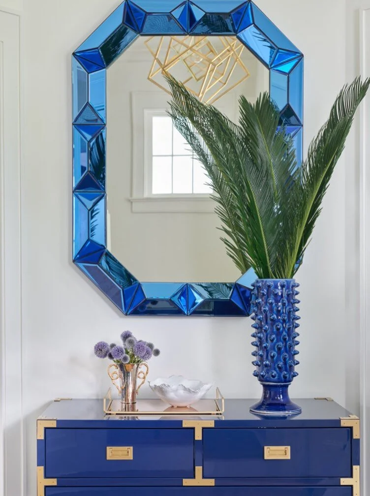First impressions are everything, and this bold blue and gold entryway makes a statement the second you walk through the door. 💙✨ The deep blue lacquer chest&mdash;finished with striking brass hardware details&mdash;pairs perfectly with the faceted 