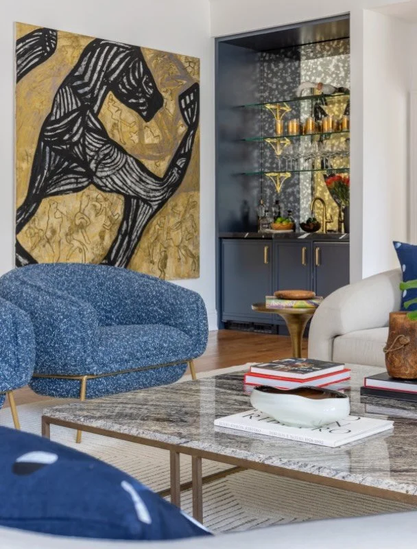 Bold textures and rich tones take center stage in this formal yet functional living room - featuring statement blue armchairs, commanding large-scale art and a sophisticated built-in bar that seamlessly blends practical elegance with modern luxury.

