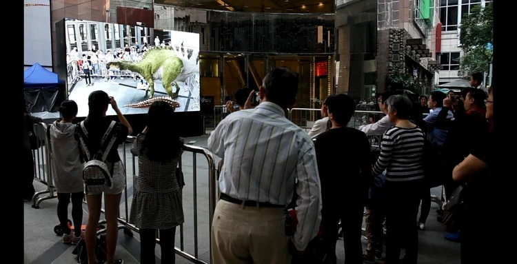 INDE's Appshaker BroadcastAR experience - visitors of the exhibit interacting with INDE's dinosaurs on a large screen