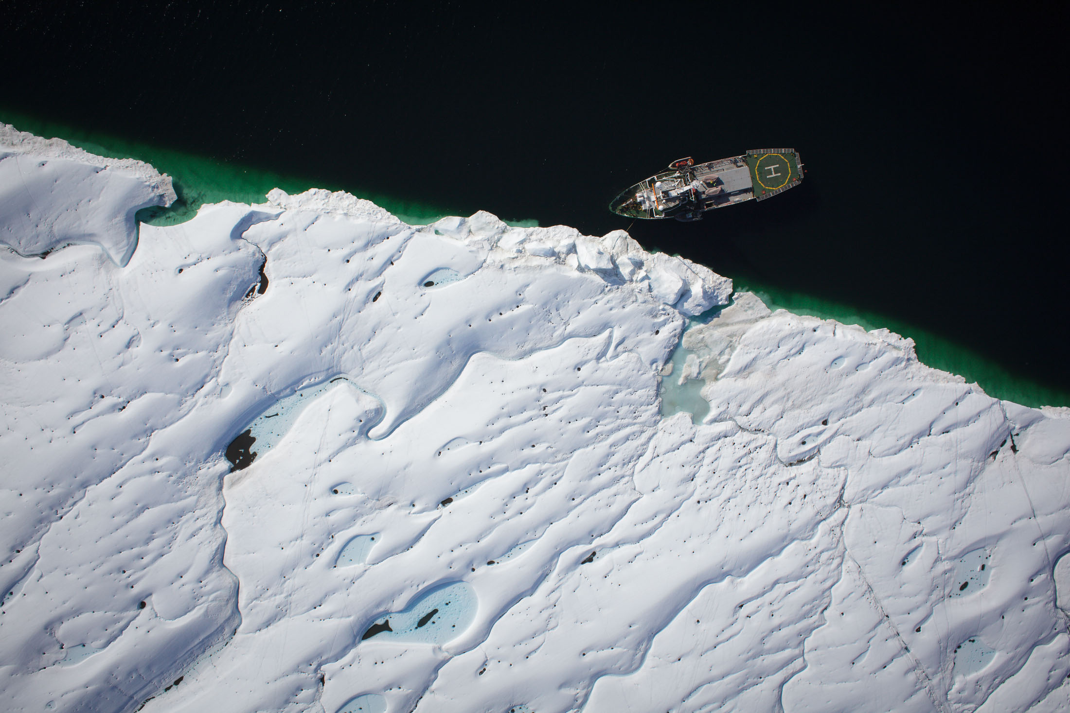Ship at a glacier's edge photographed from the air