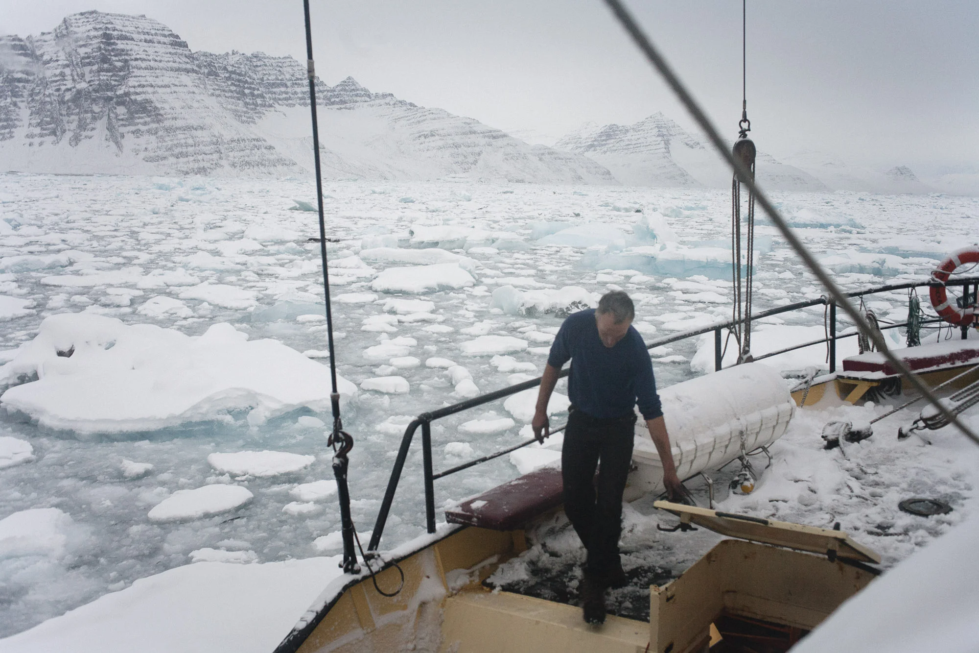 Gert on the deck of Noorderlicht with mountains behind