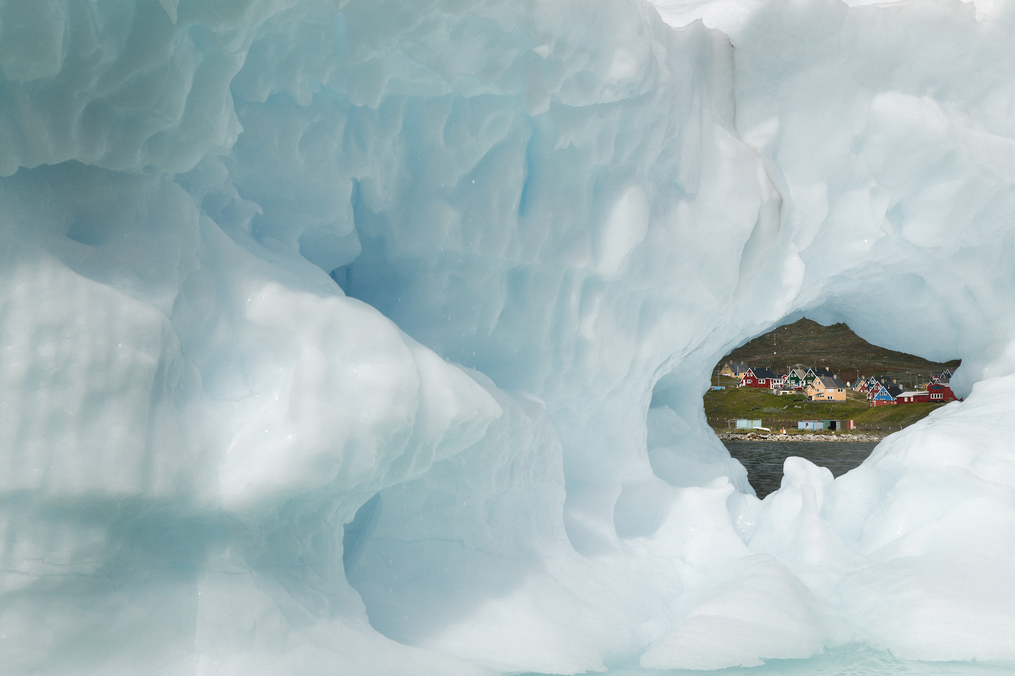 A hole in an iceberg reveals Greenlandic town